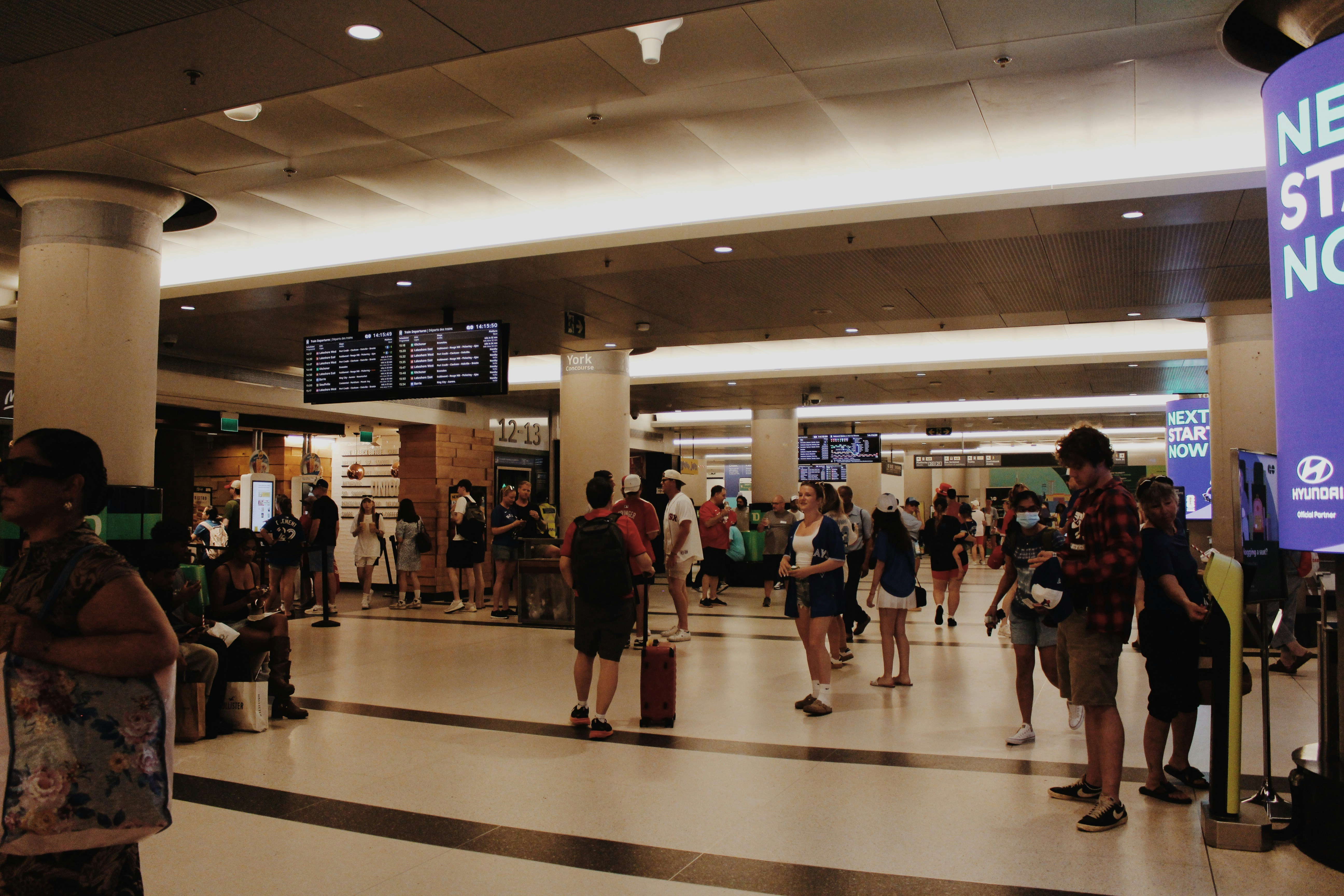 Travelers with luggage navigate a bustling indoor station.