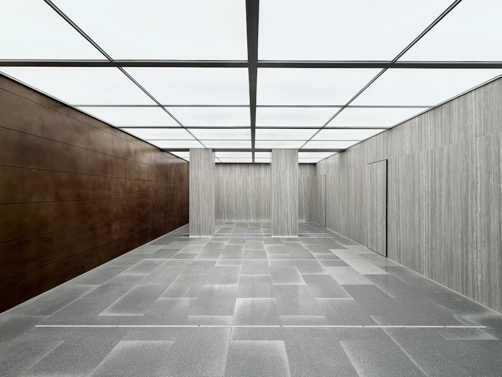 A daylit interior with a terrazzo floor, timber-lined walls and a glazed roof