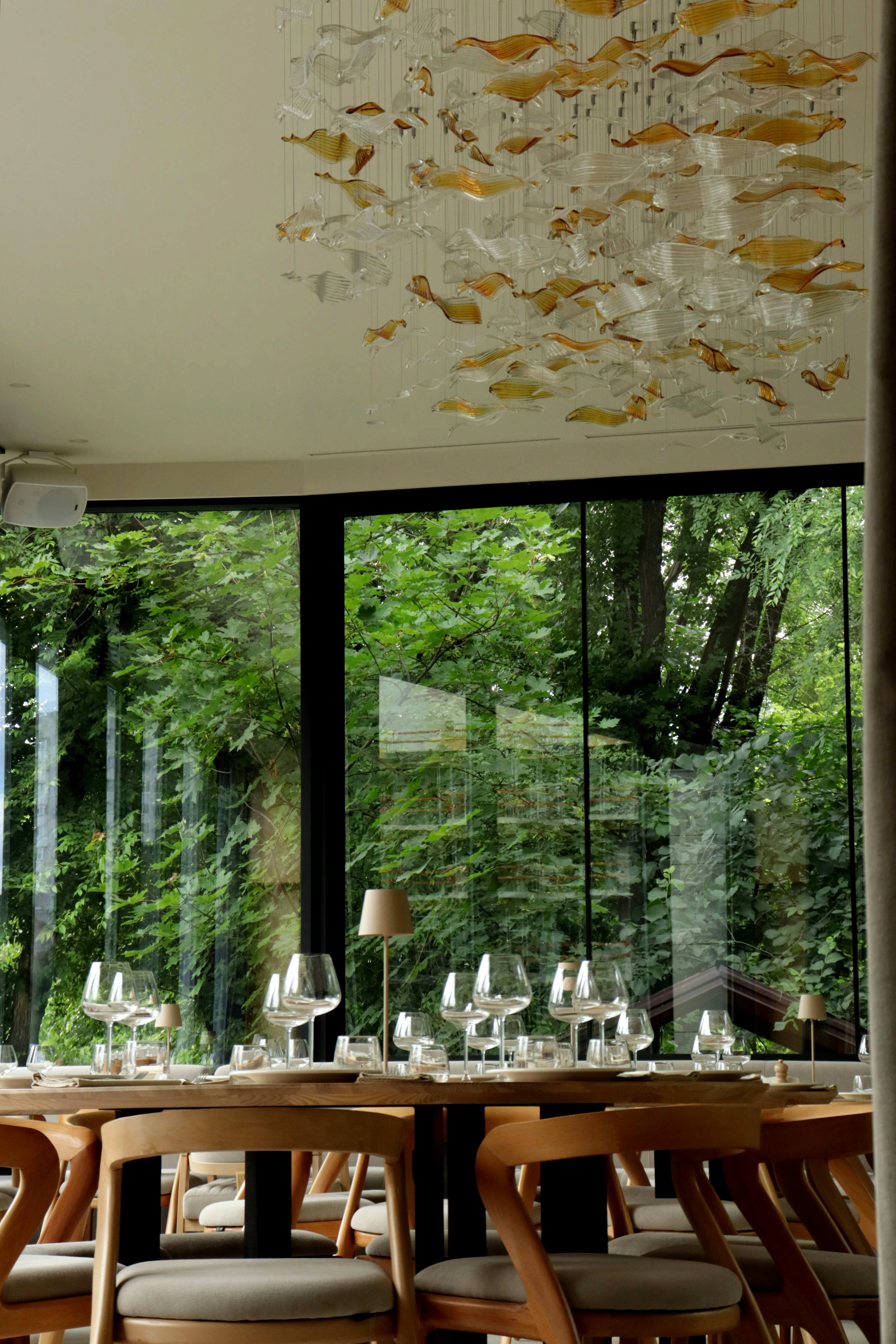 Elegante restaurante con vistas al bosque y lámpara decorativa.
