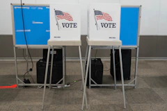 Two voting booths with American flags and the word VOTE on their privacy screens