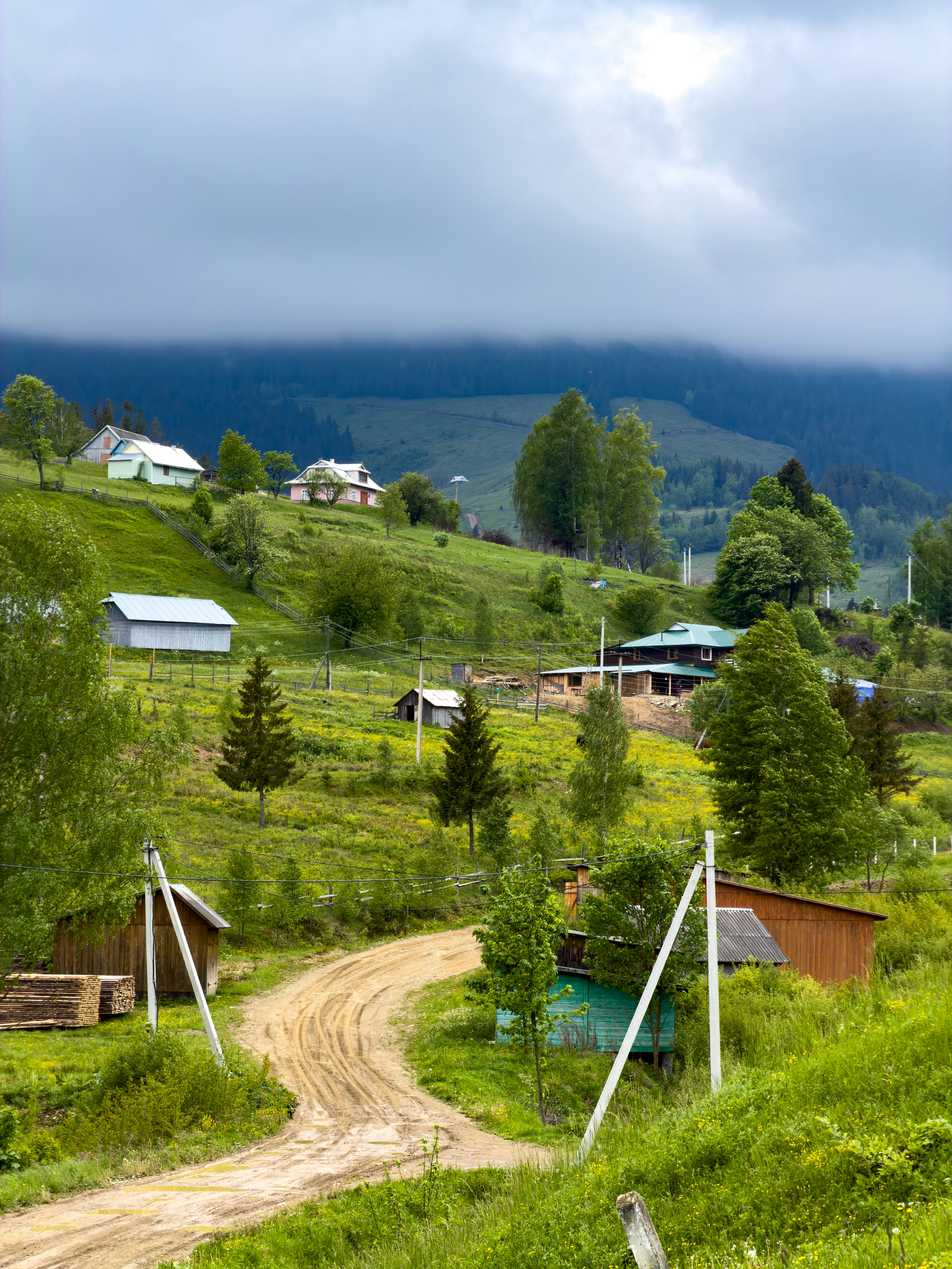 Winding dirt road through a village on green hills