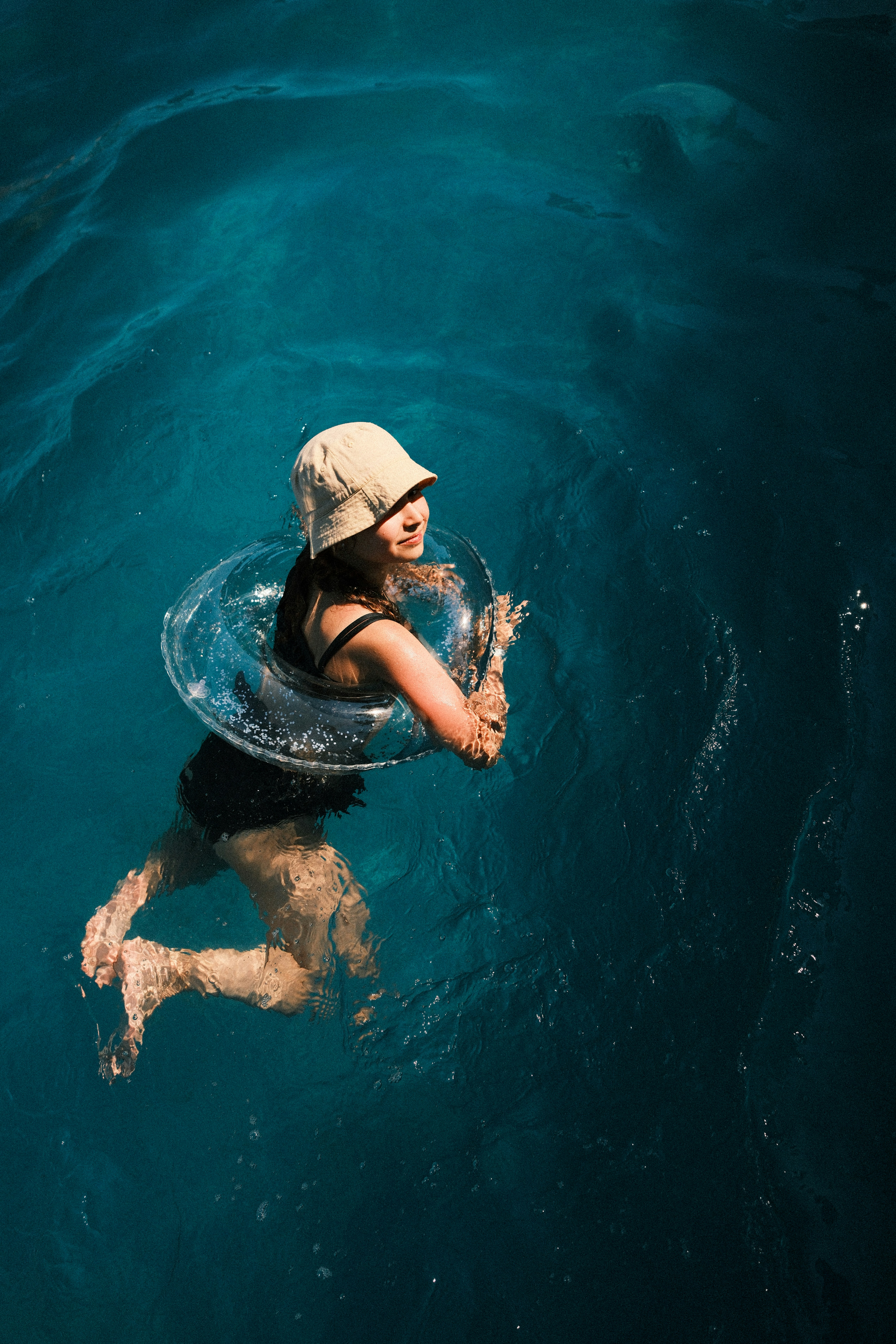Woman in hat swimming with clear inflatable ring