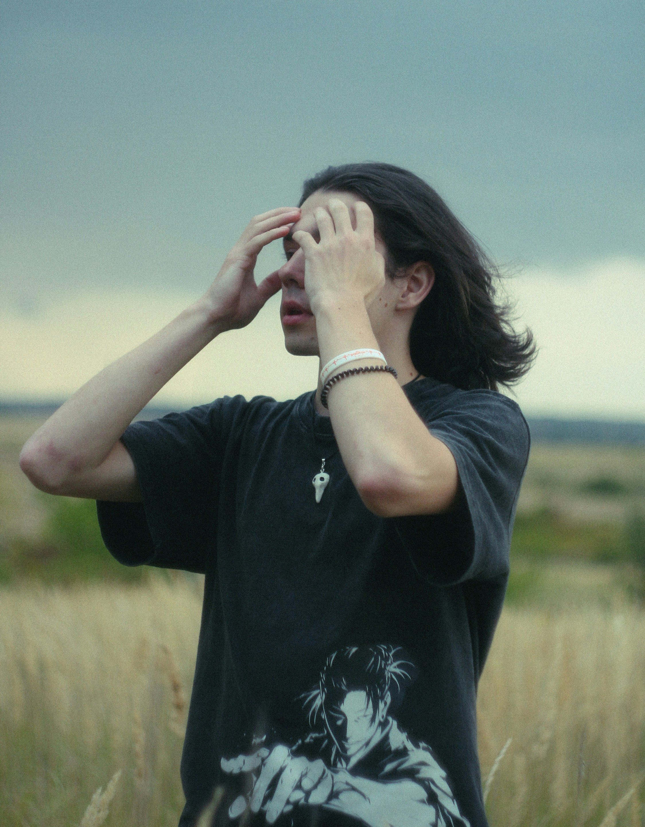 Person with long hair stands in a grassy field