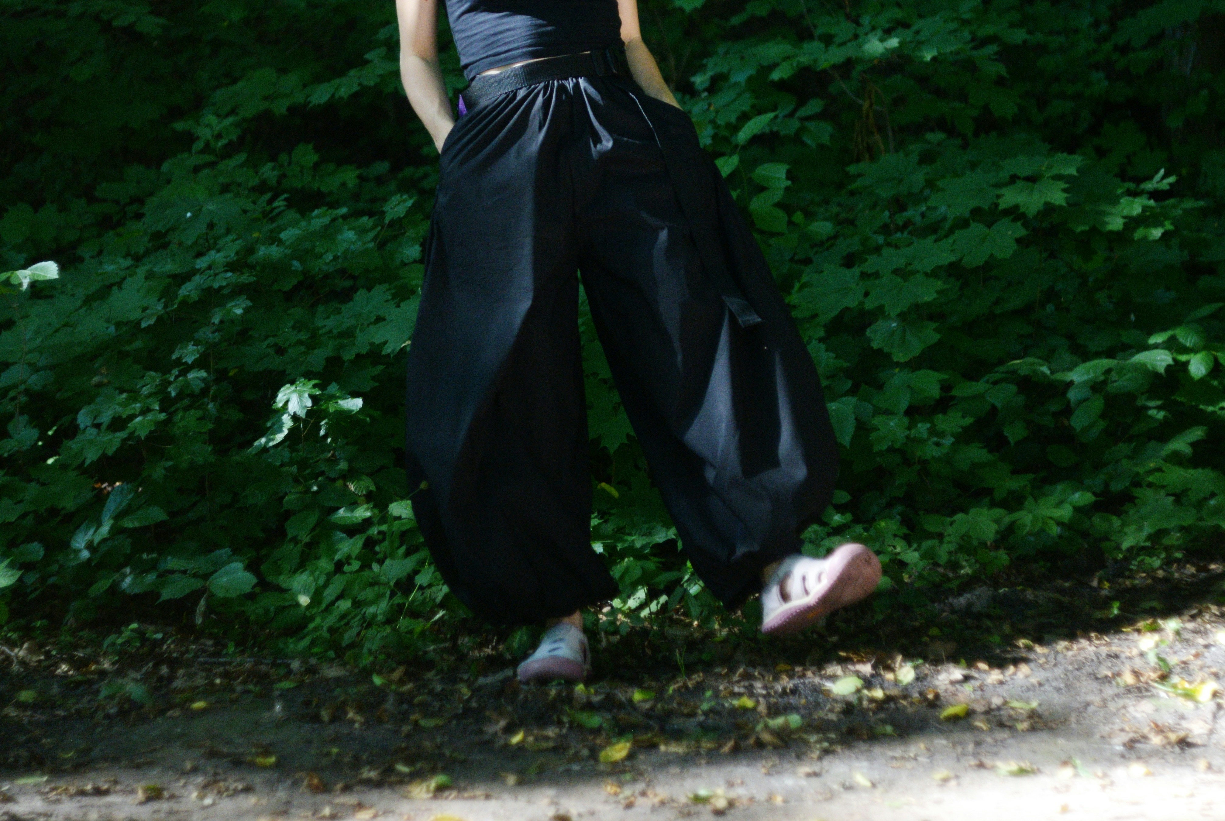 A person's legs in black baggy pants and pink shoes.