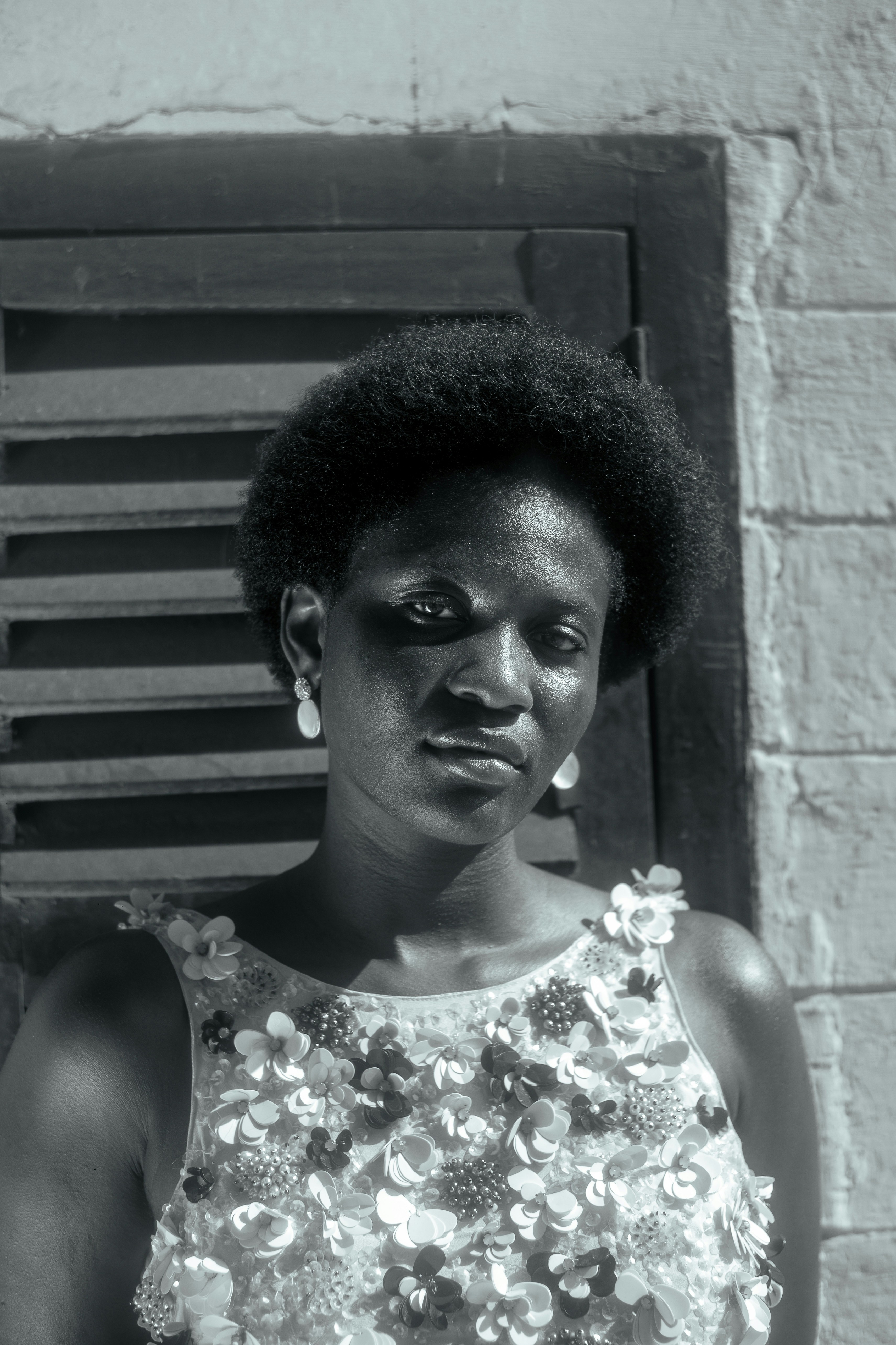 Woman with afro and floral top stands by a window