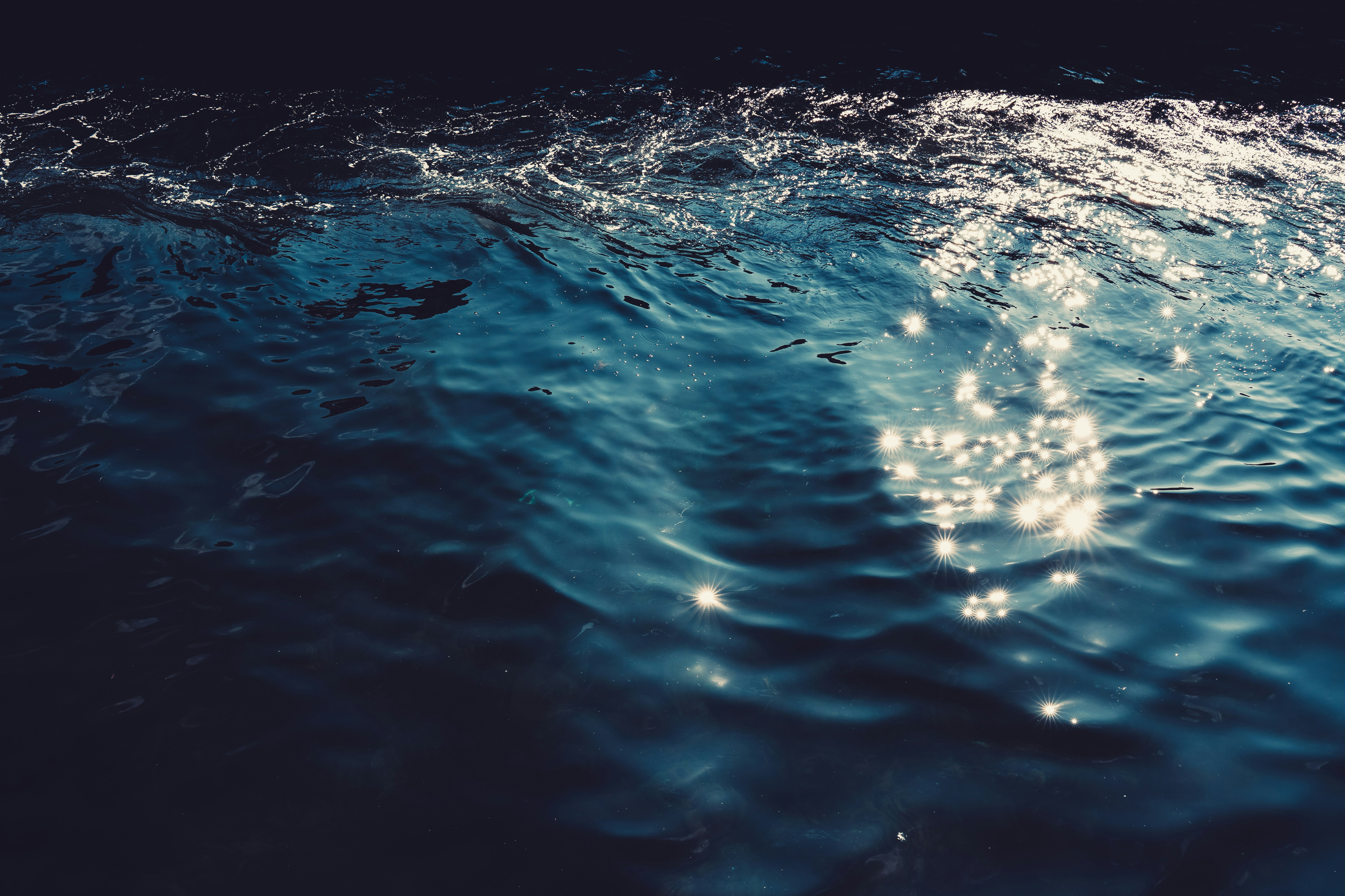 Dark blue ocean waves with sparkling sunlight reflections