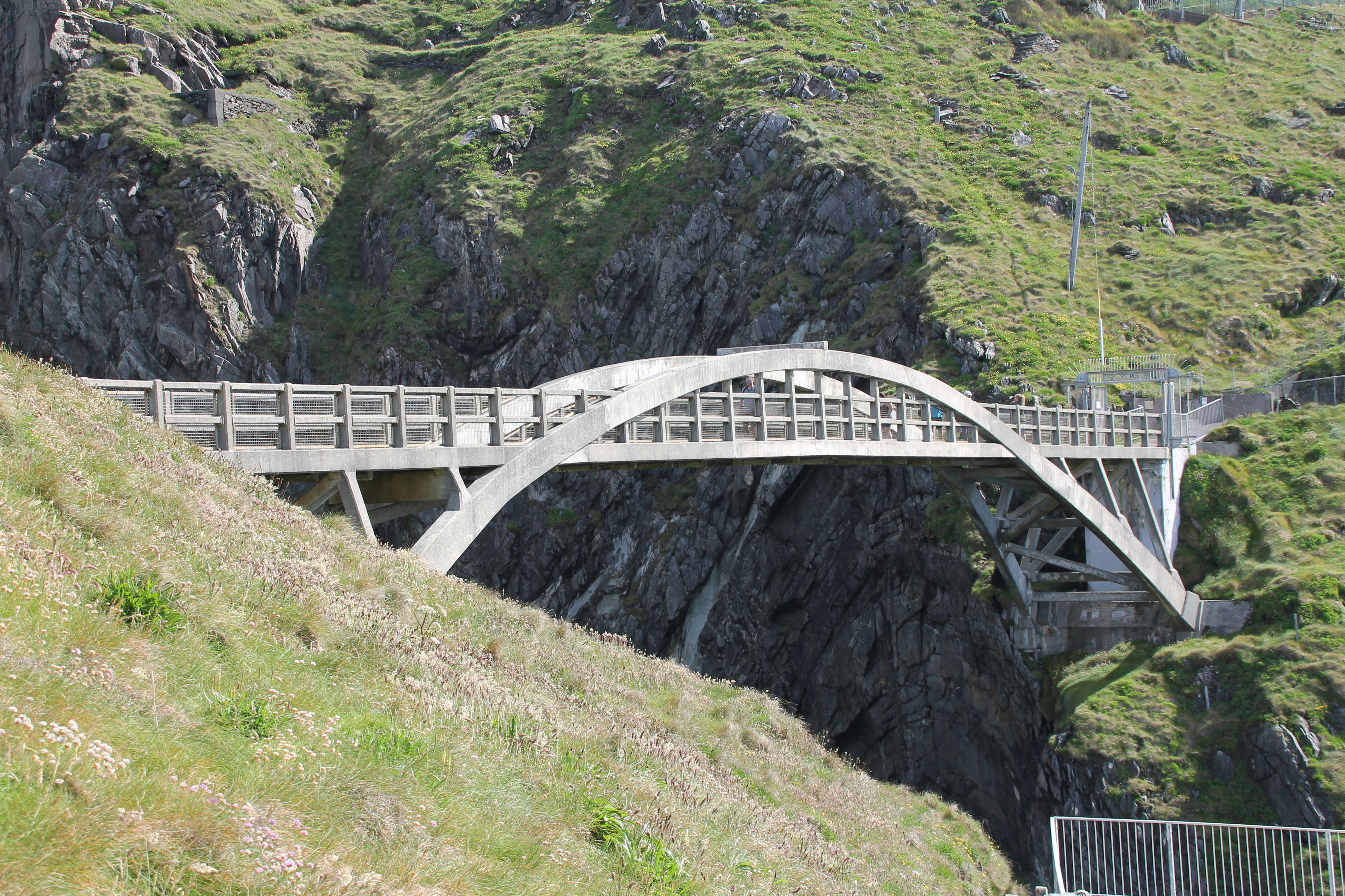 Un ponte ad arco collega due rigogliose colline rocciose.