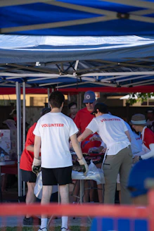 Volunteers organize items under a blue tent outdoors.