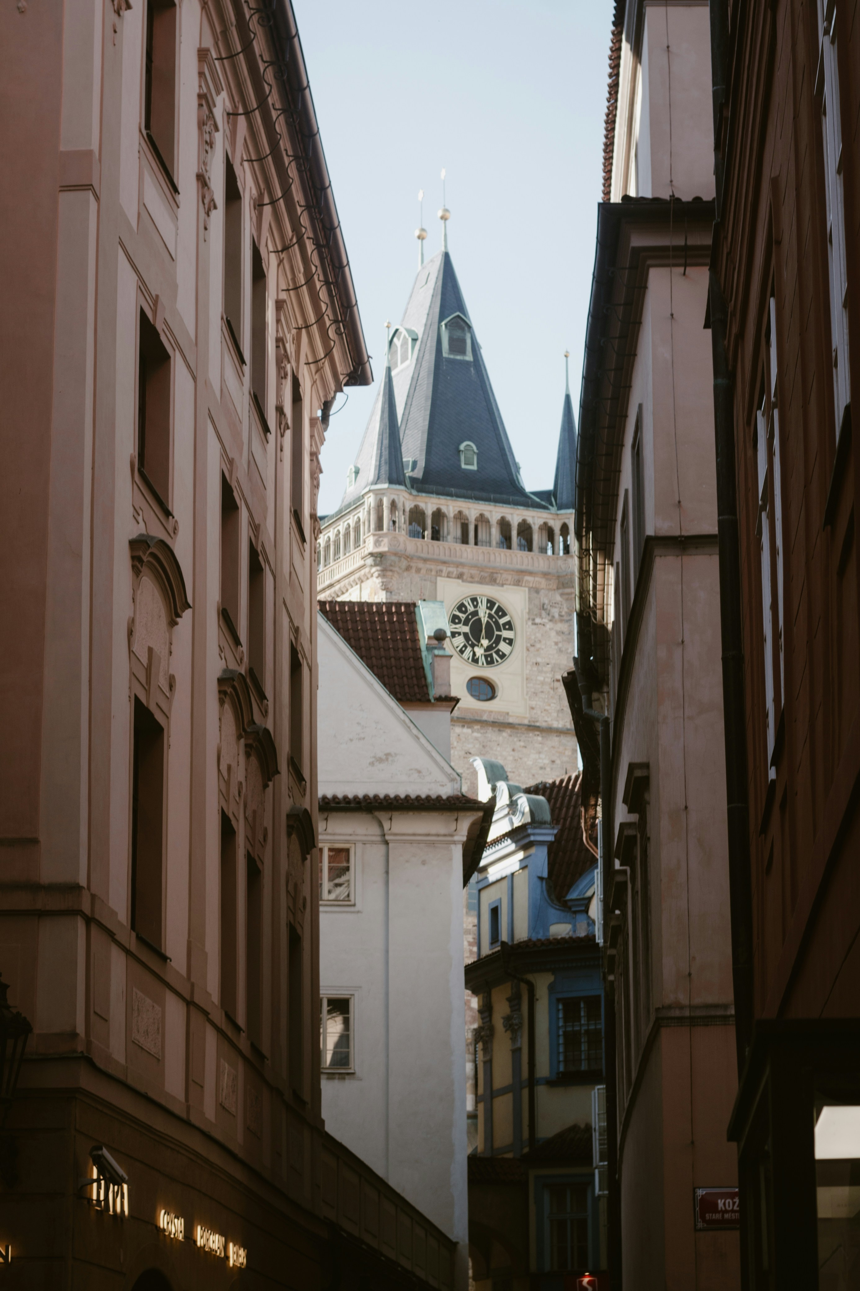 A narrow street frames a historic clock tower.