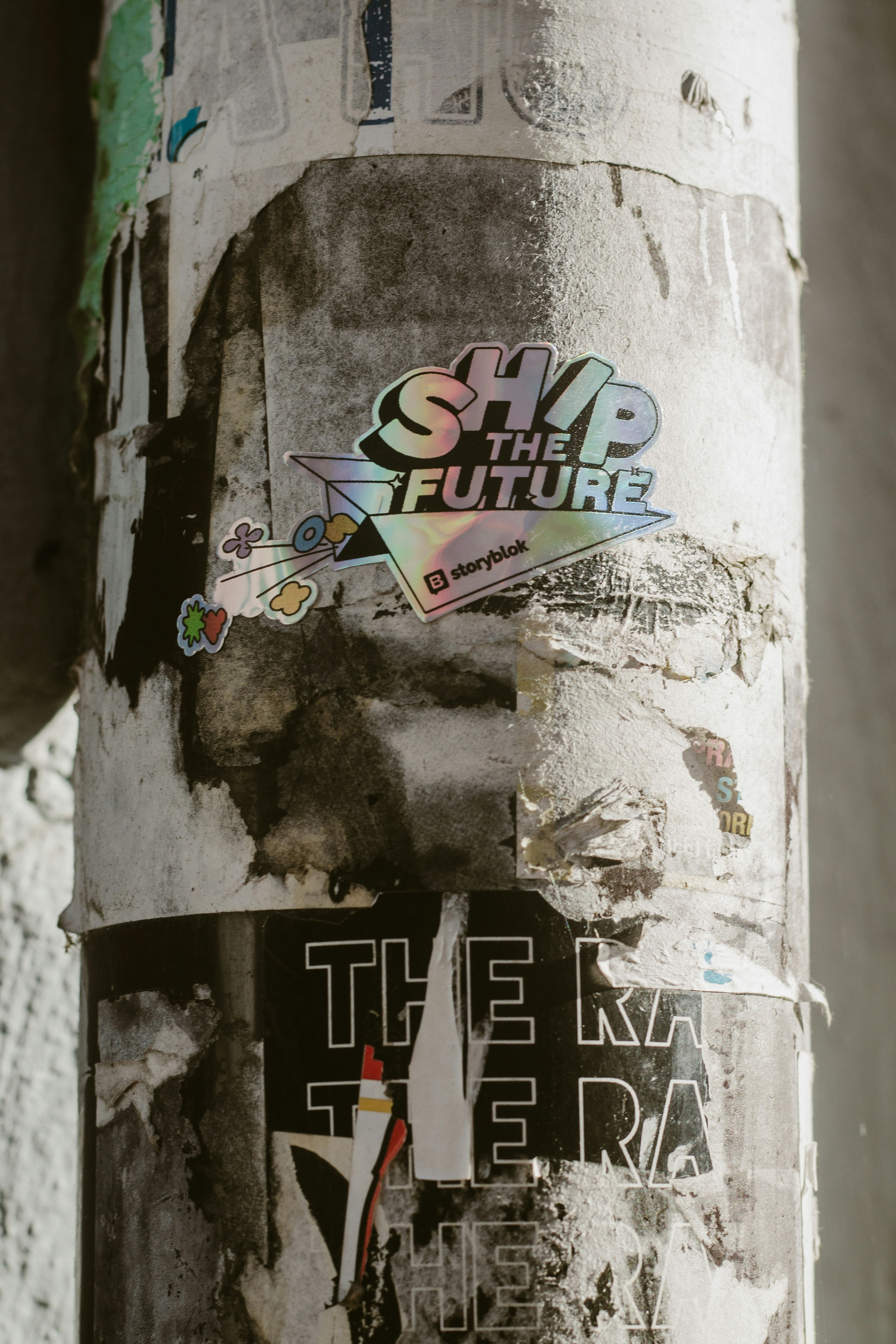 Holographic 'ship the future' sticker on a weathered street pole.