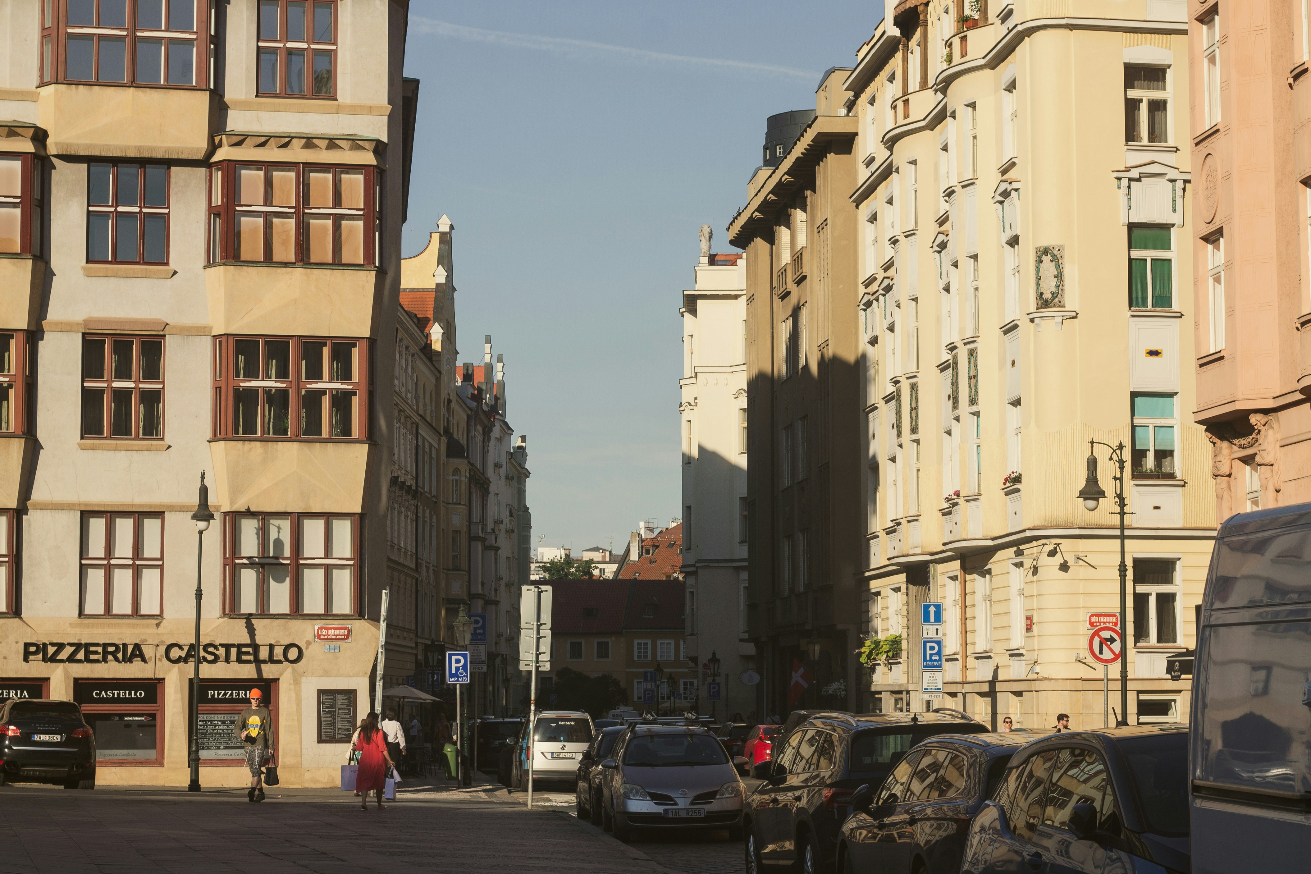 Sunny city street lined with traditional buildings and cars.