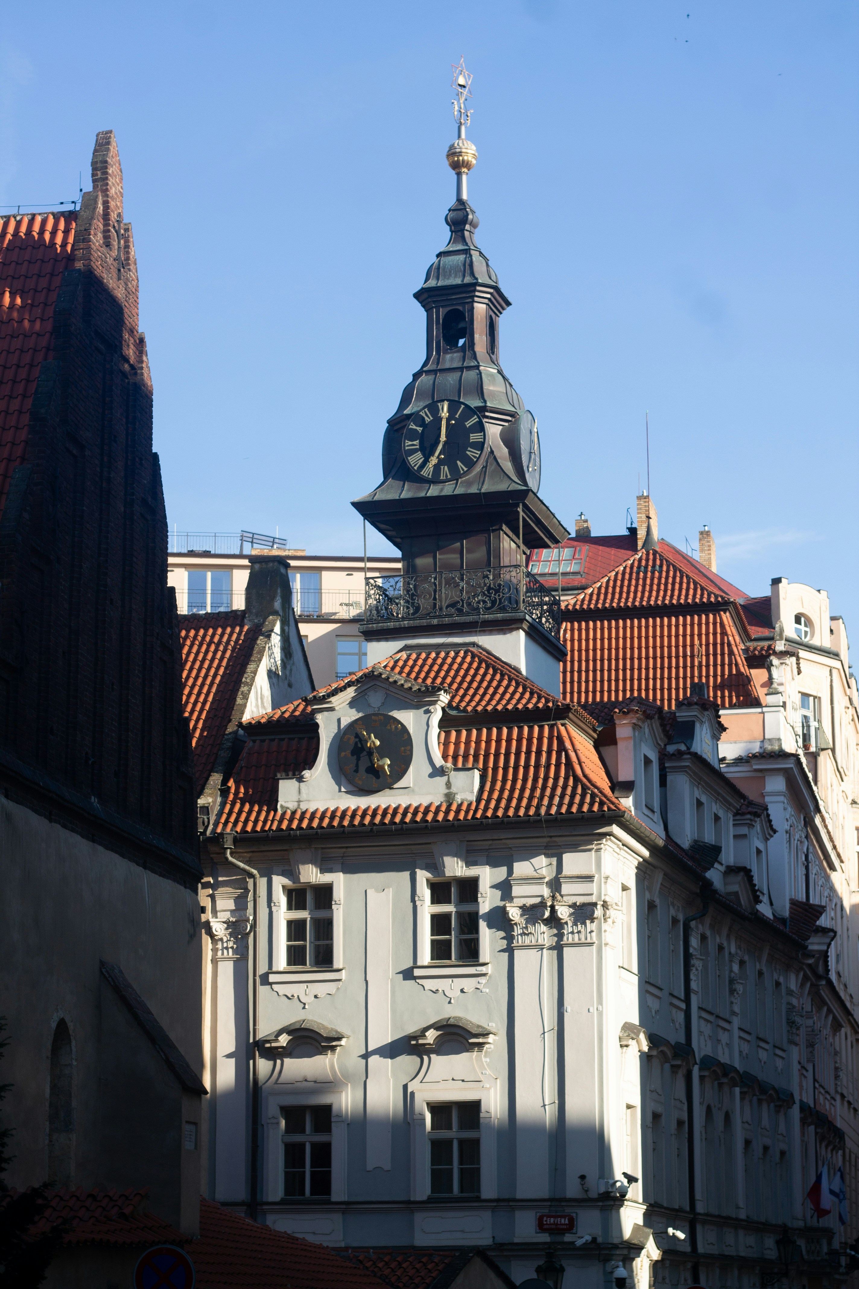 Historic clock tower rises above old buildings with red roofs.