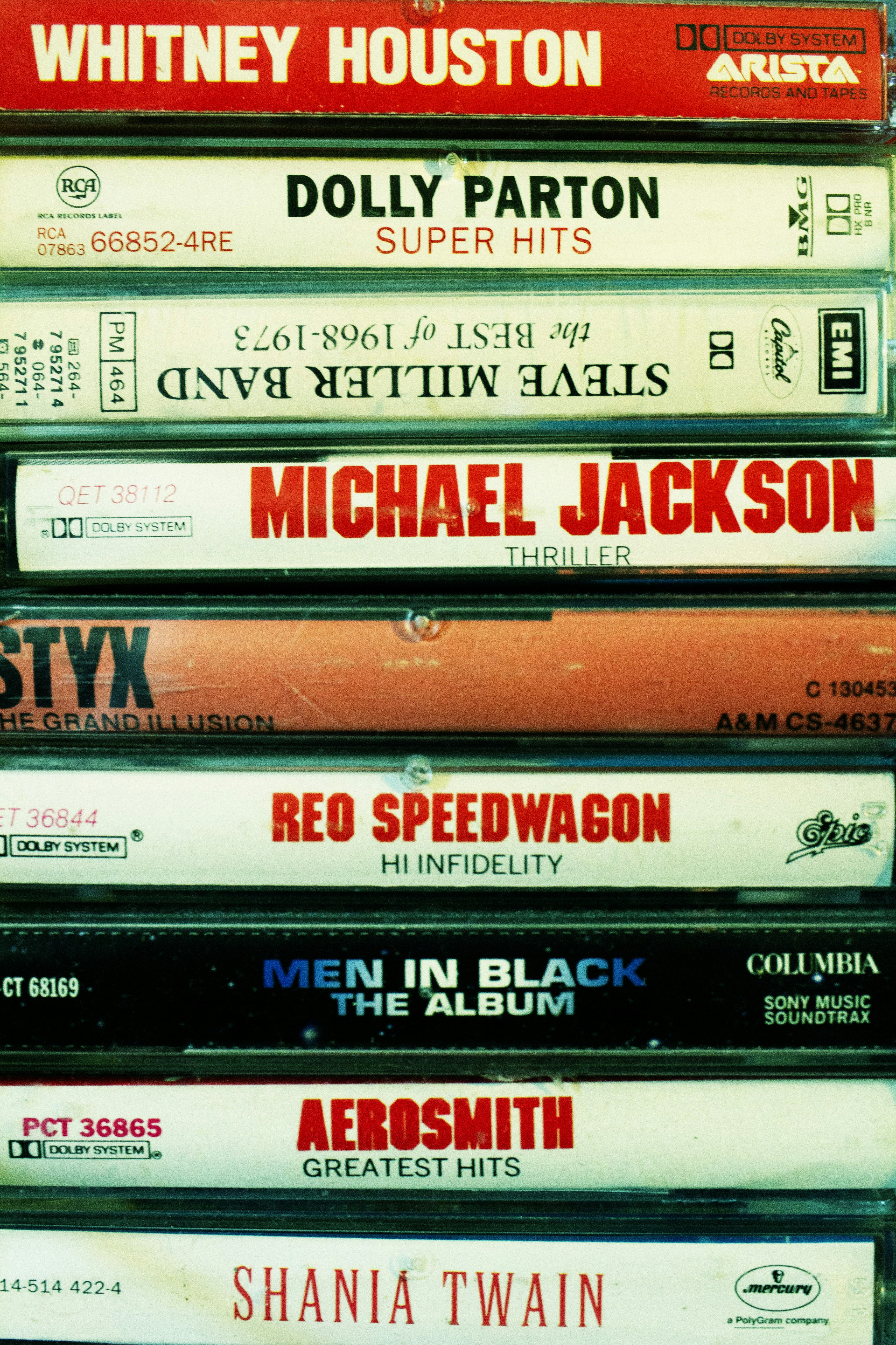 Stacked vintage music cassette tapes by various artists.