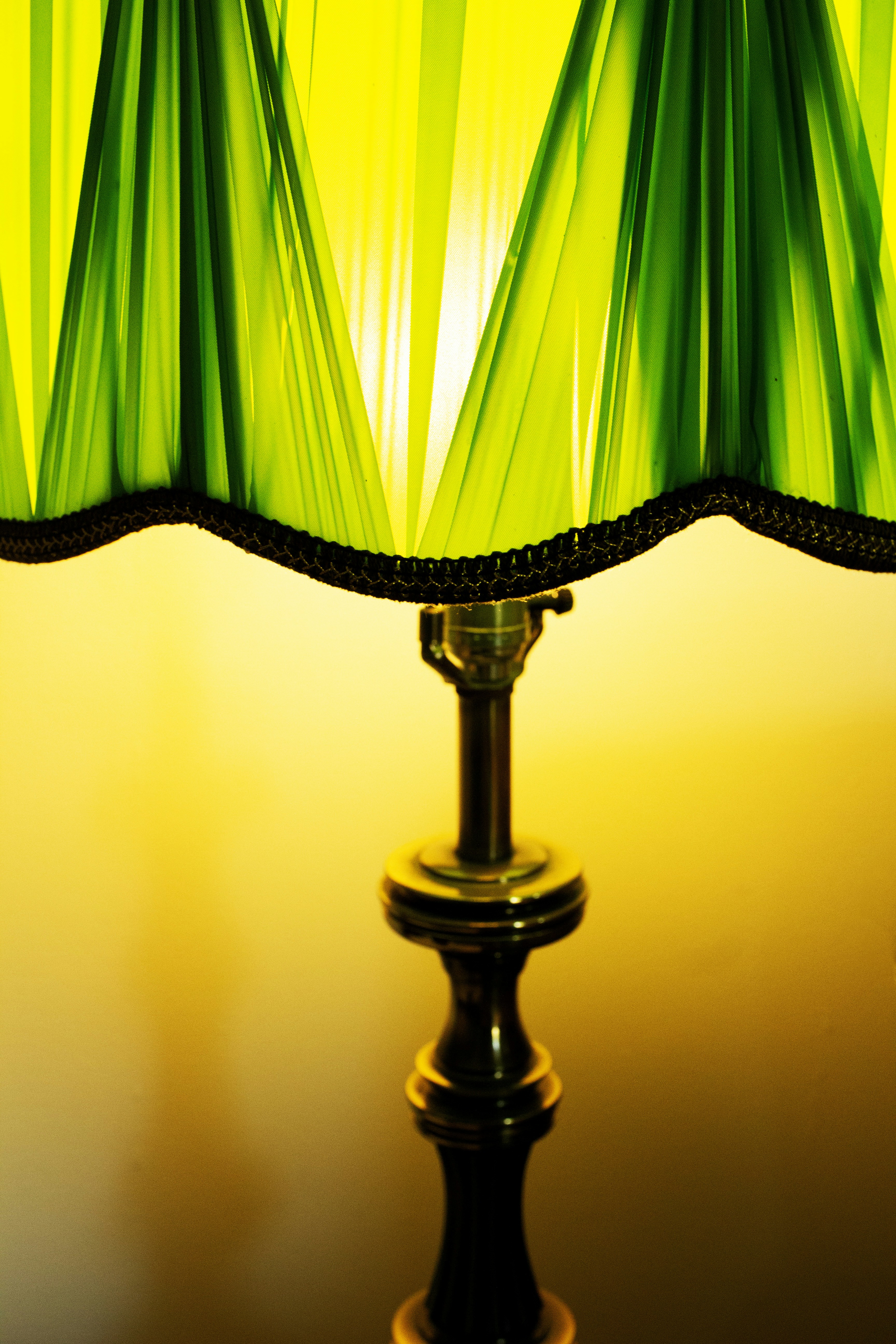 Abat-jour plissé vert avec lumière jaune chaude.