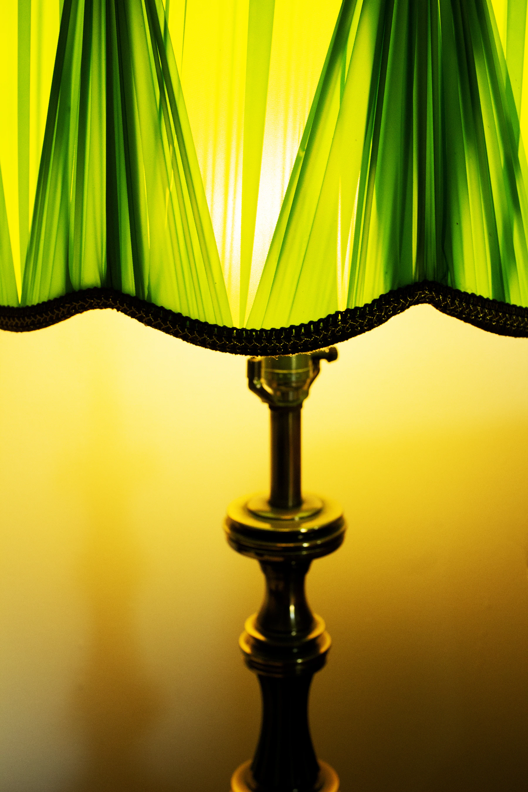 A green glass banker's lamp glowing yellow, close up