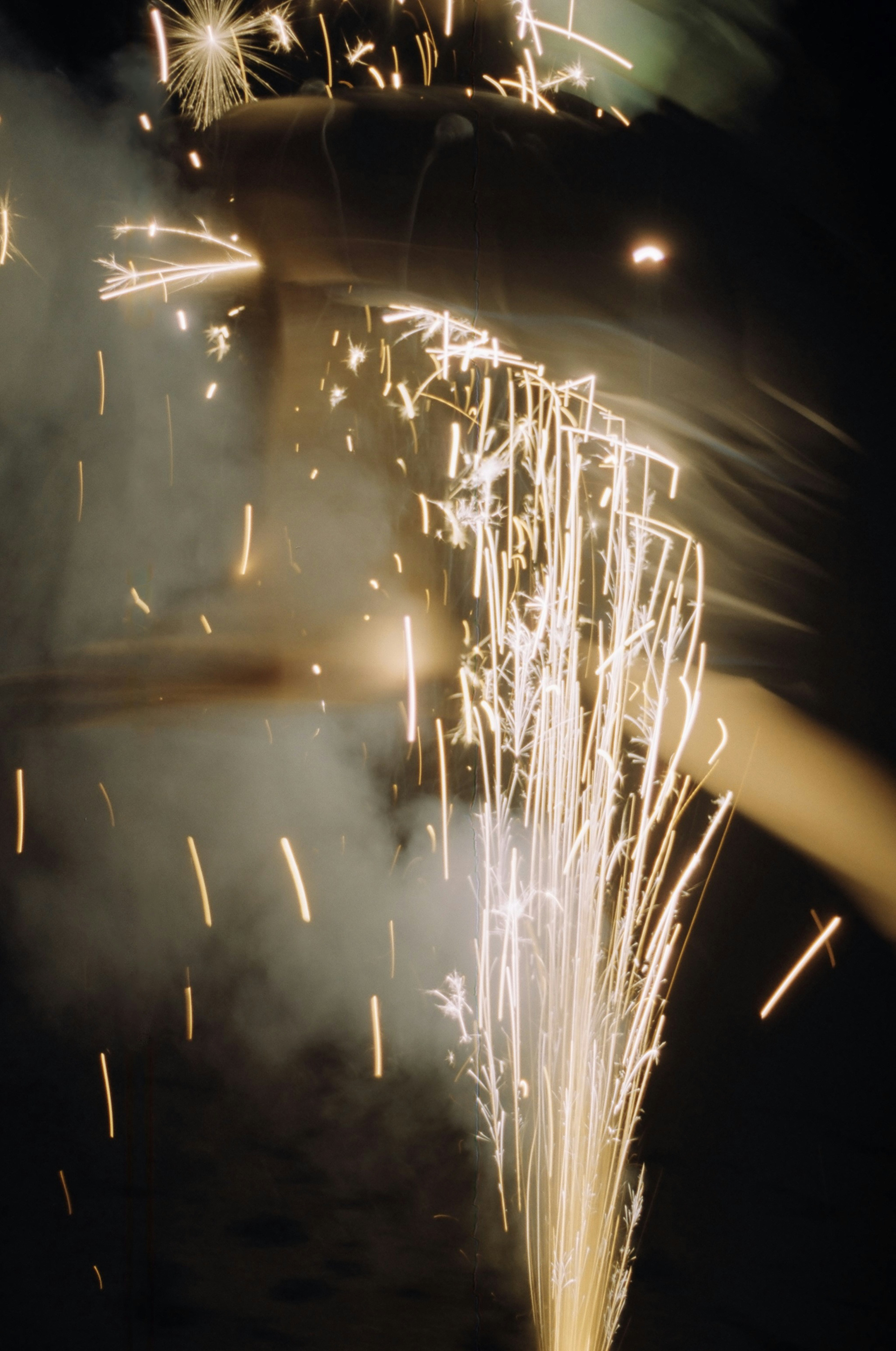 Bright sparks and smoke from a firework in the dark.