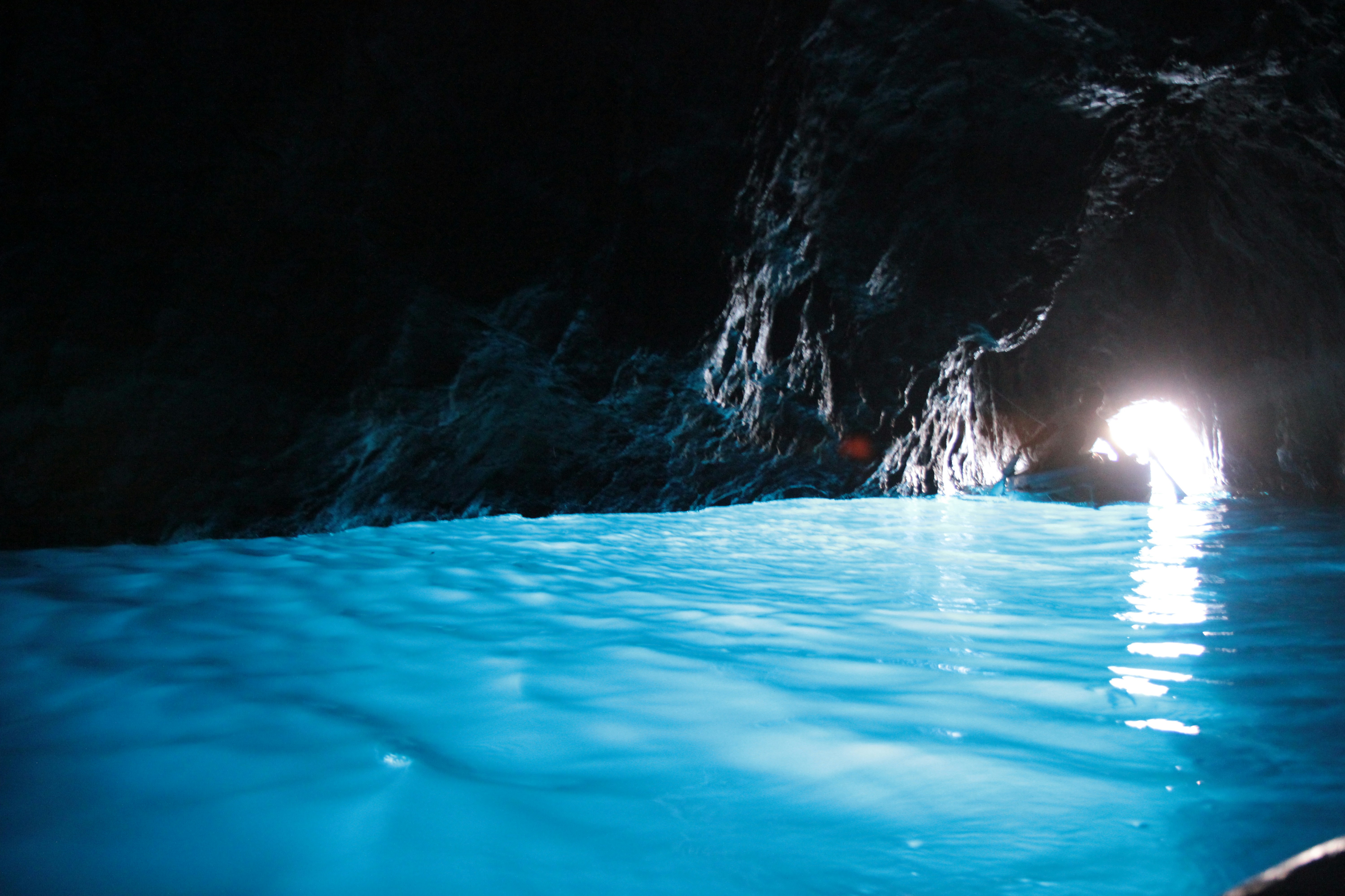 Glowing blue water inside a dark sea cave.