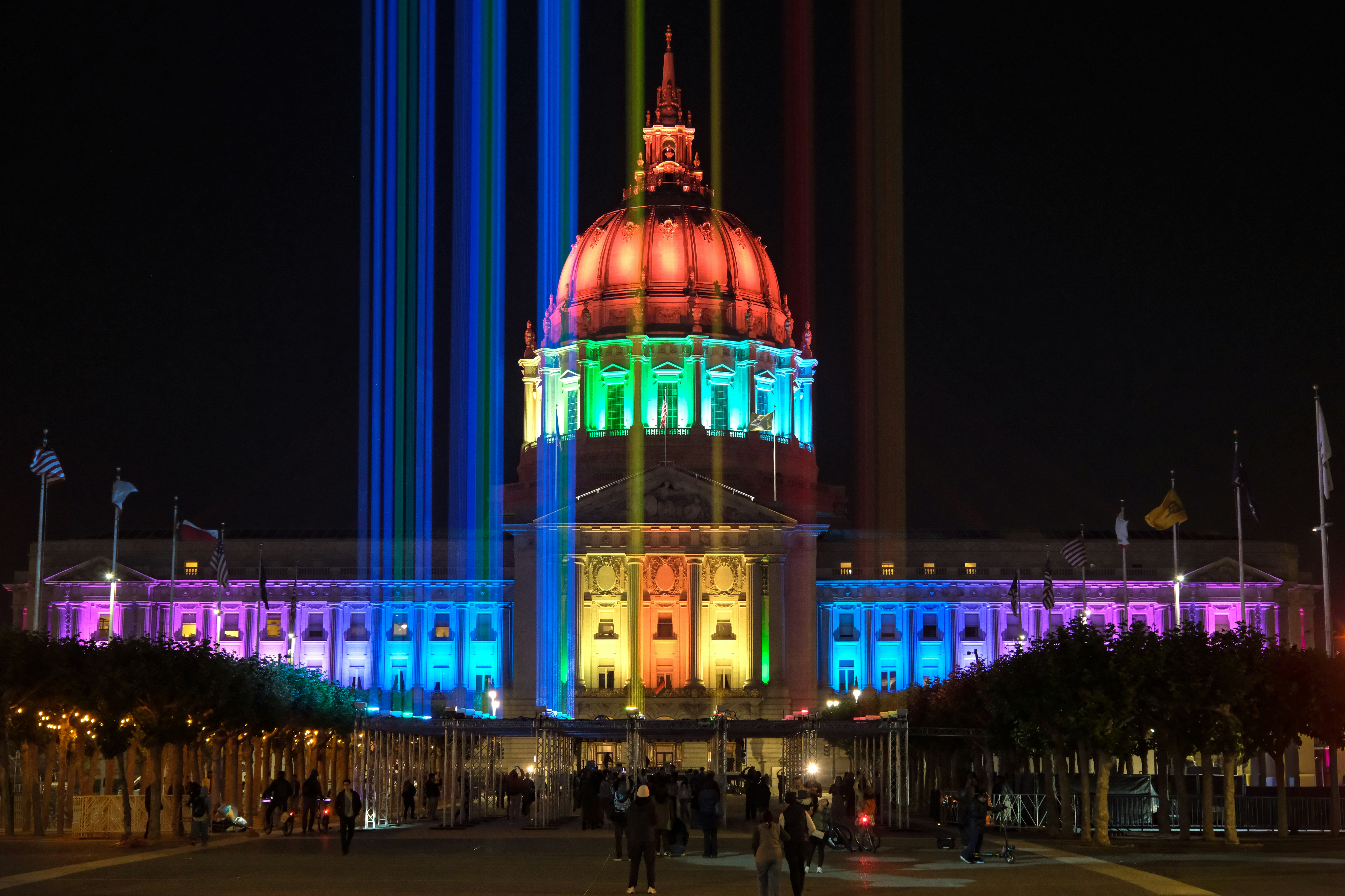 Grand domed building illuminated with vibrant rainbow lights at night.