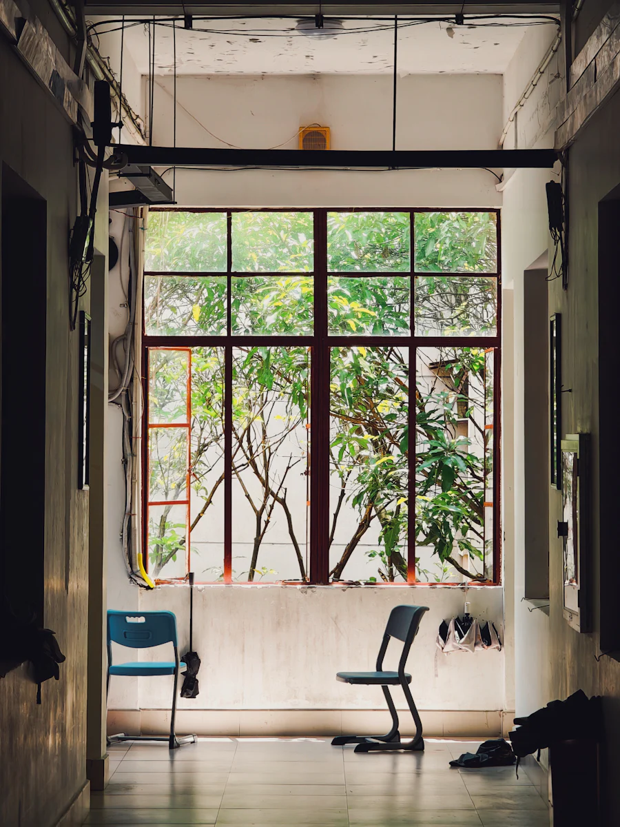 Two chairs beside a large window looking out on green trees.