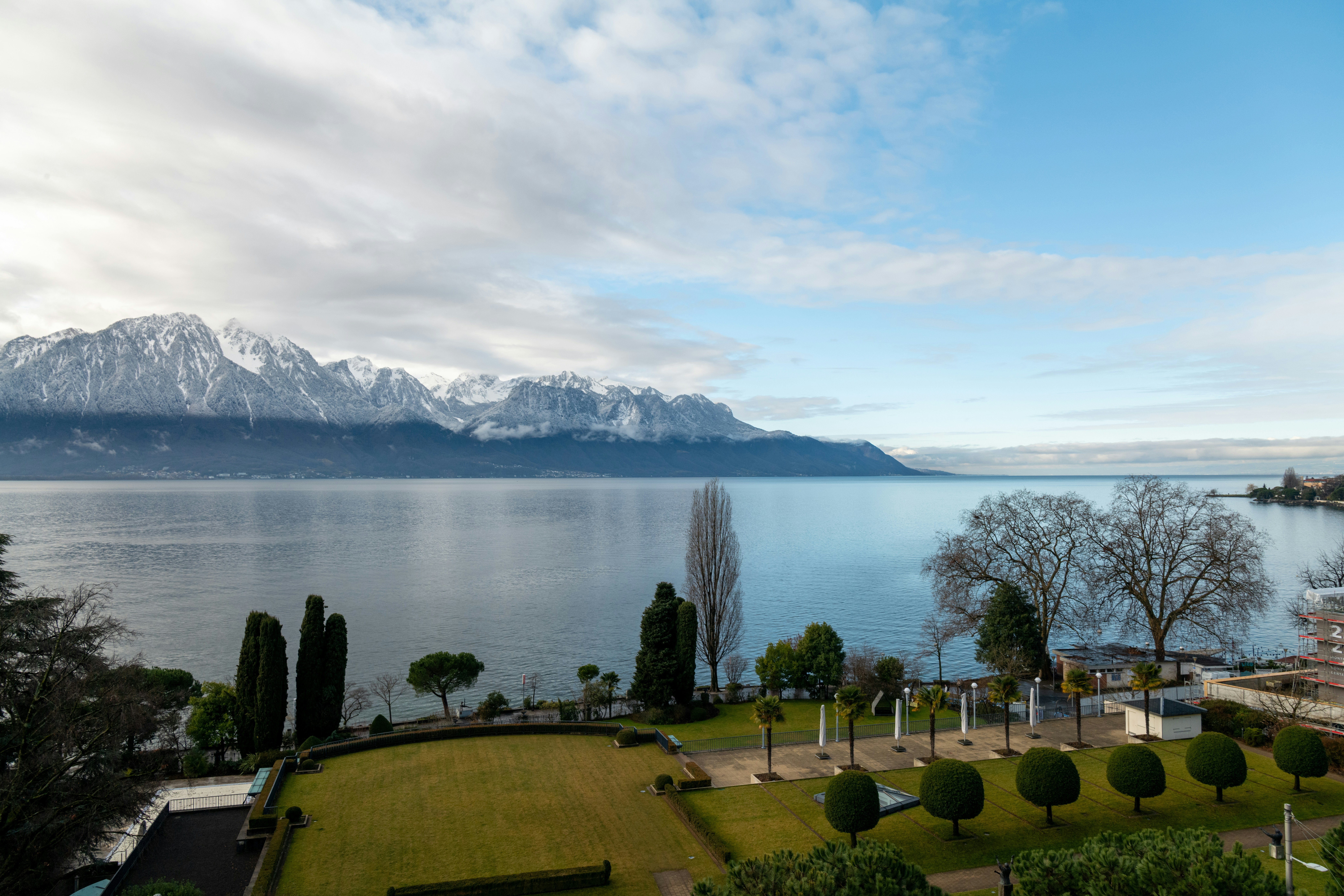 Snow-capped mountains overlooking a tranquil lake and garden.
