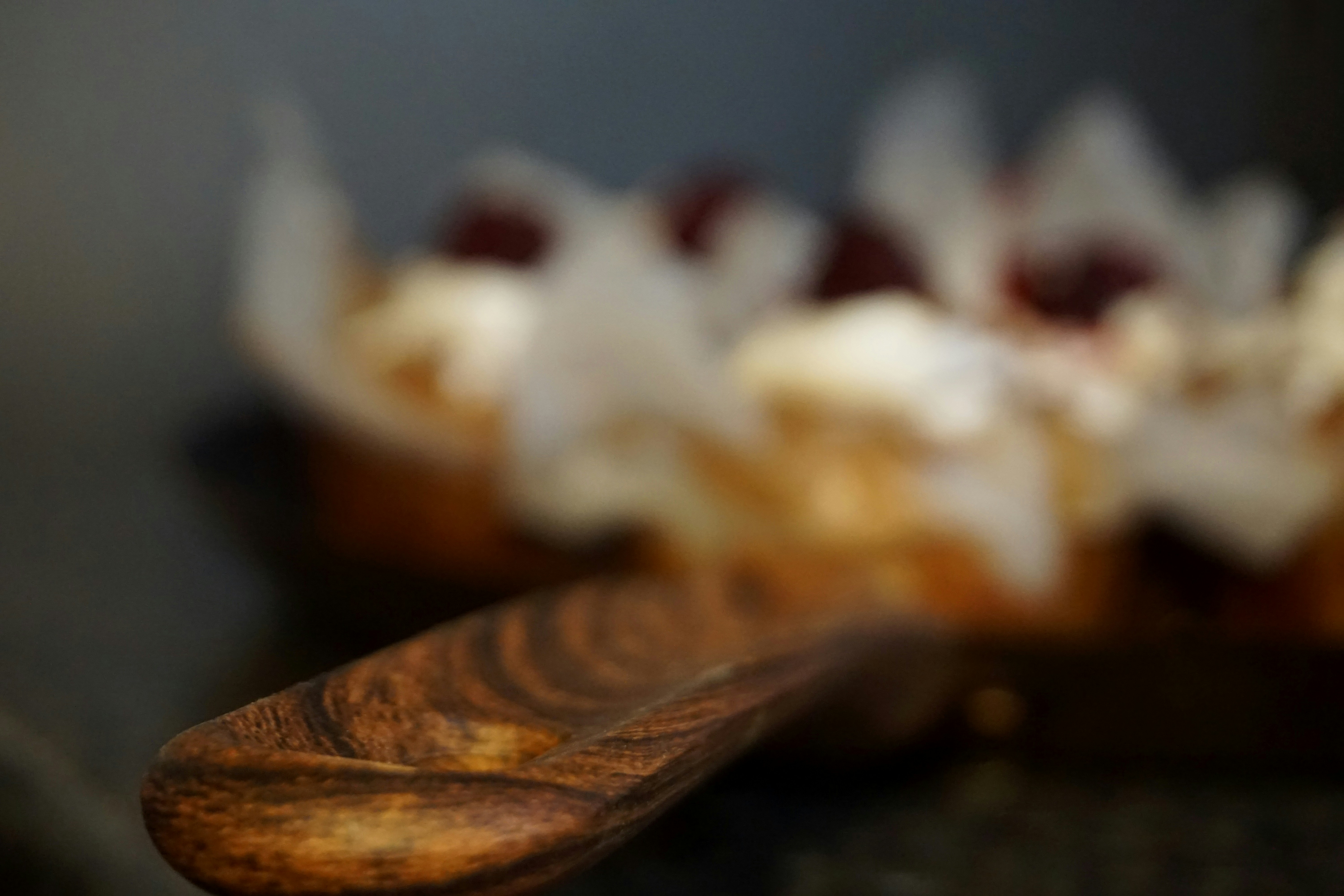 Textured wooden spoon in front of blurry pastries.