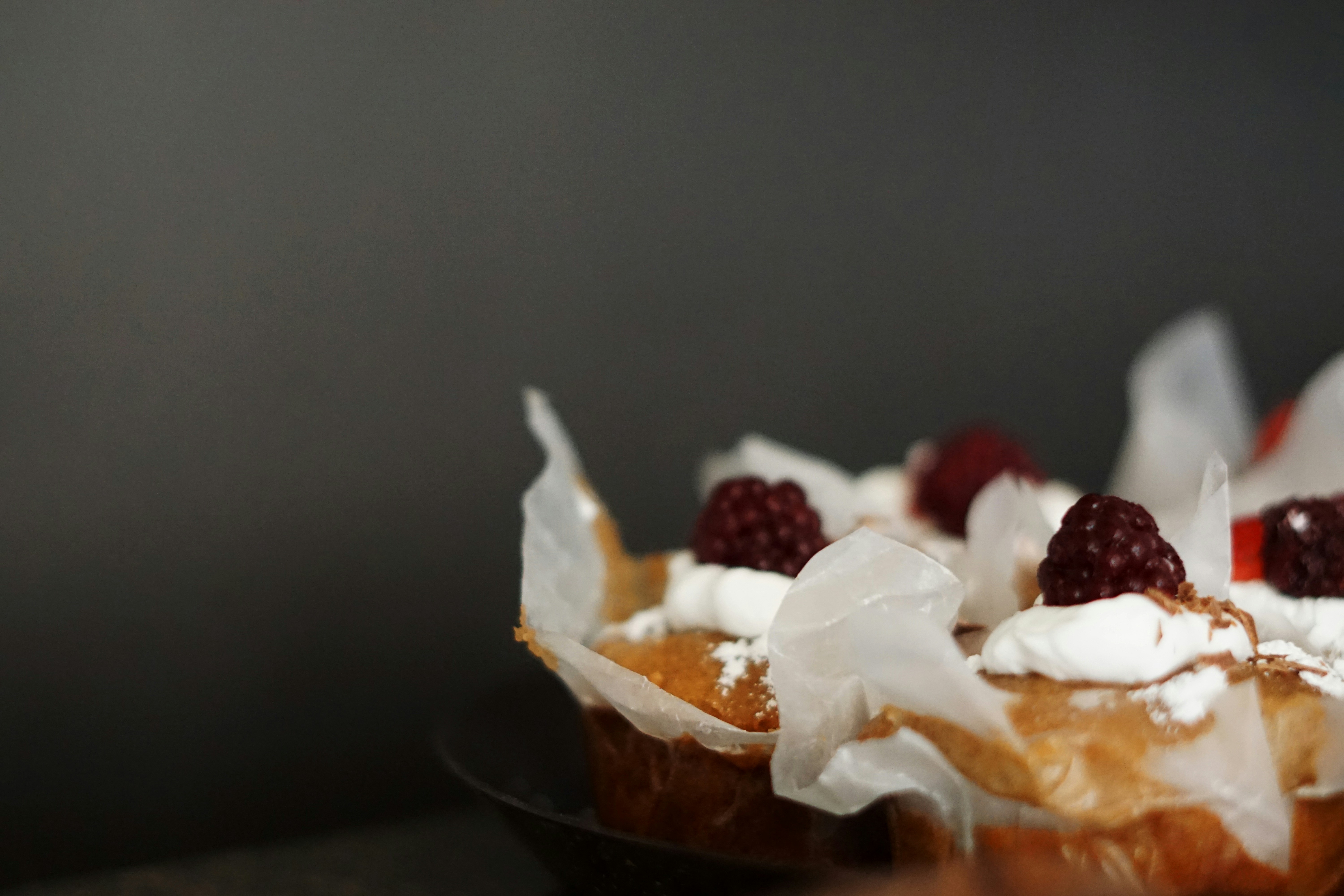 Cupcakes with white frosting and blackberries on a dark background.