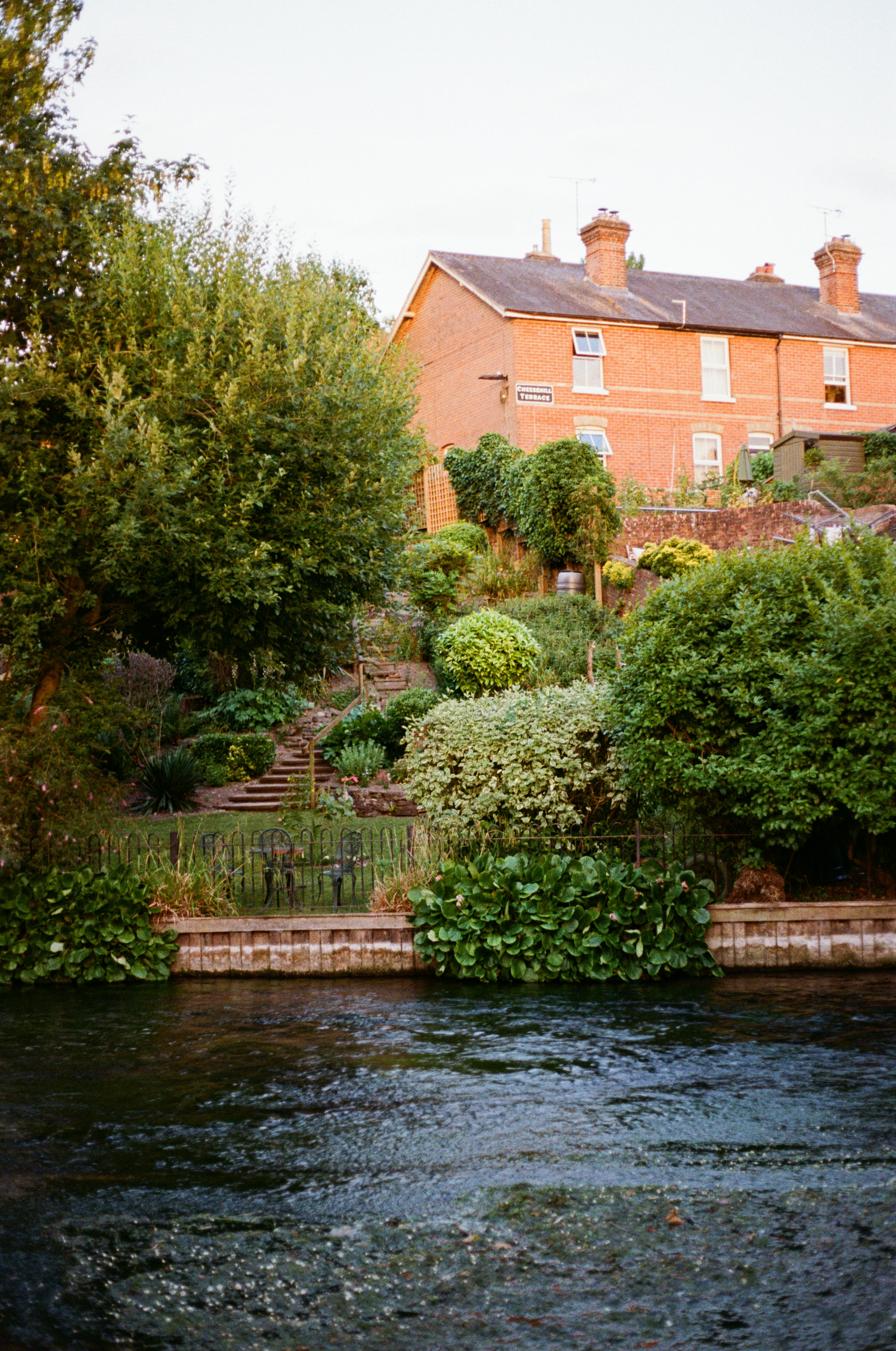 Brick house overlooking a river with terraced garden
