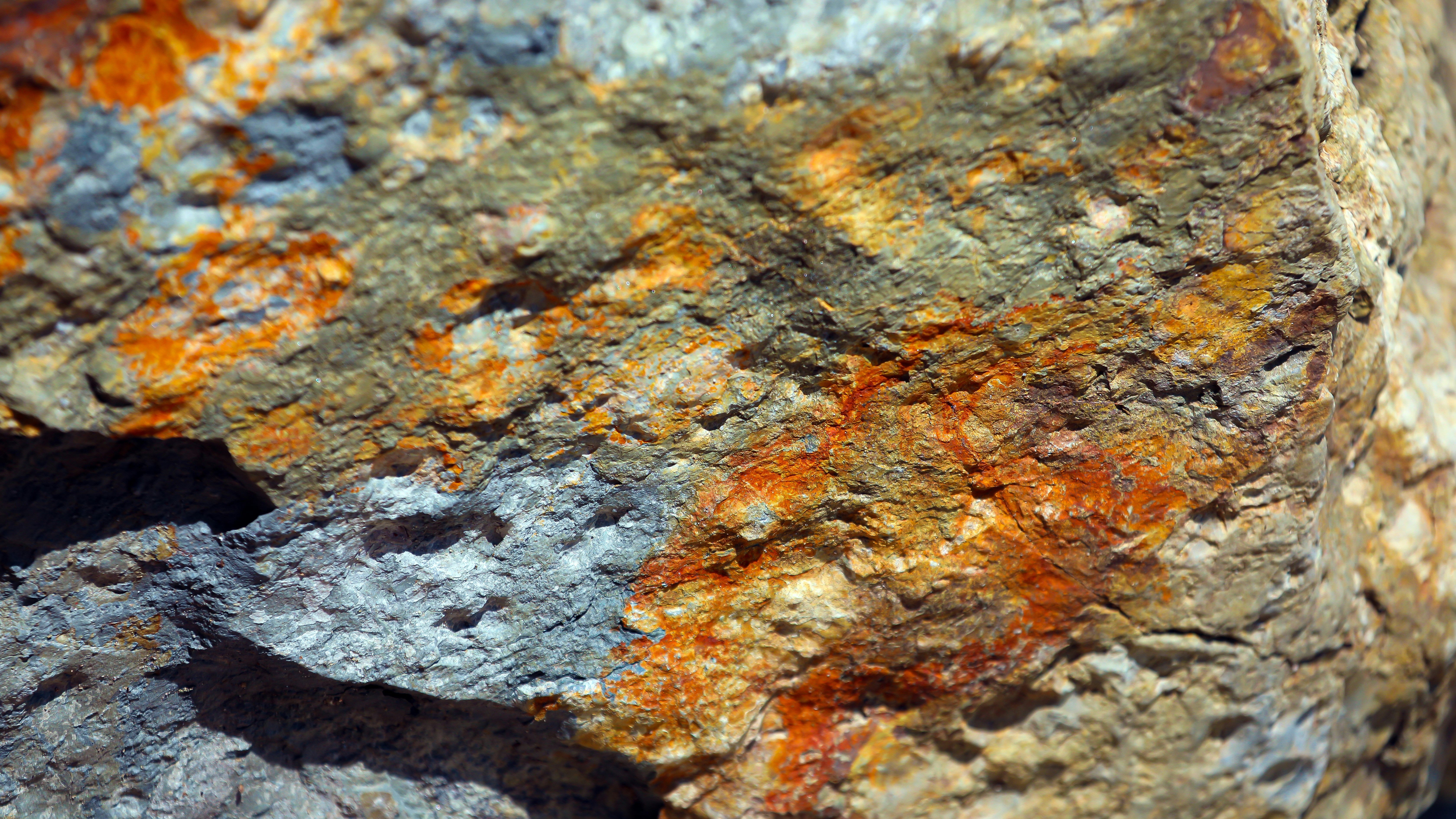 Bunte Mineralgesteinstextur mit Orange, Grün und Grau.