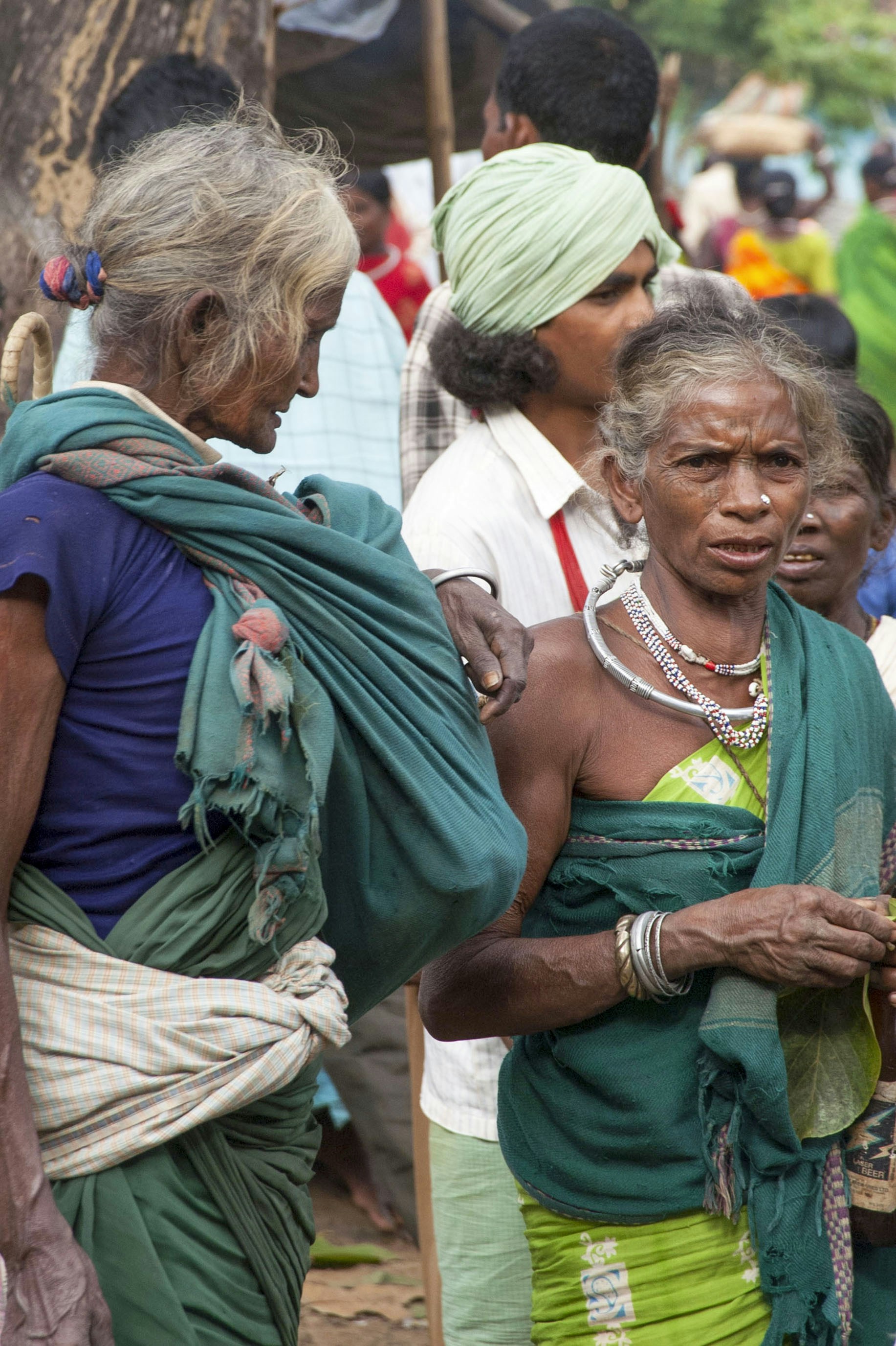 Duas senhoras idosas com trajes tradicionais, uma carregando um bebê.