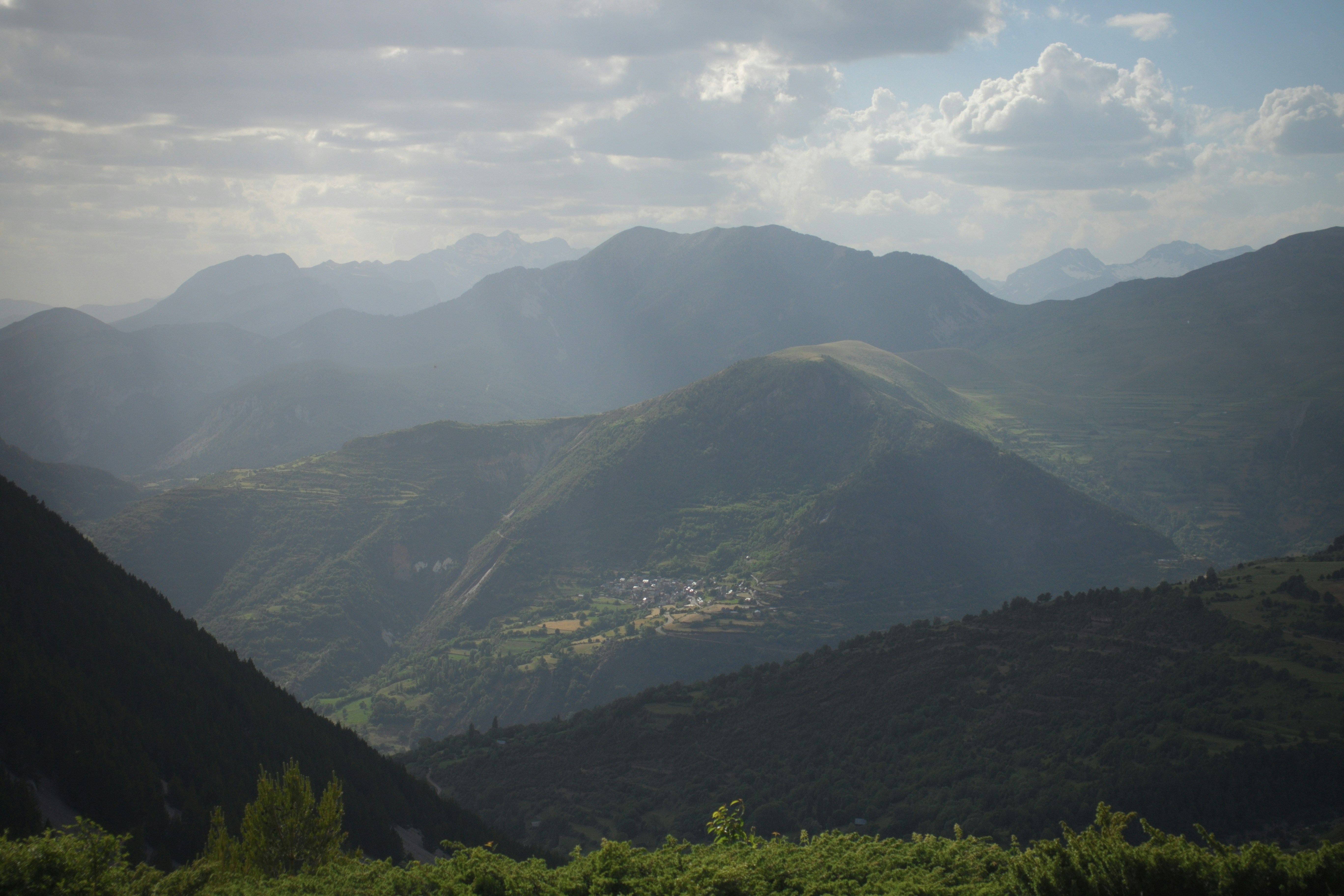 Hazy mountain landscape with a valley and distant village.