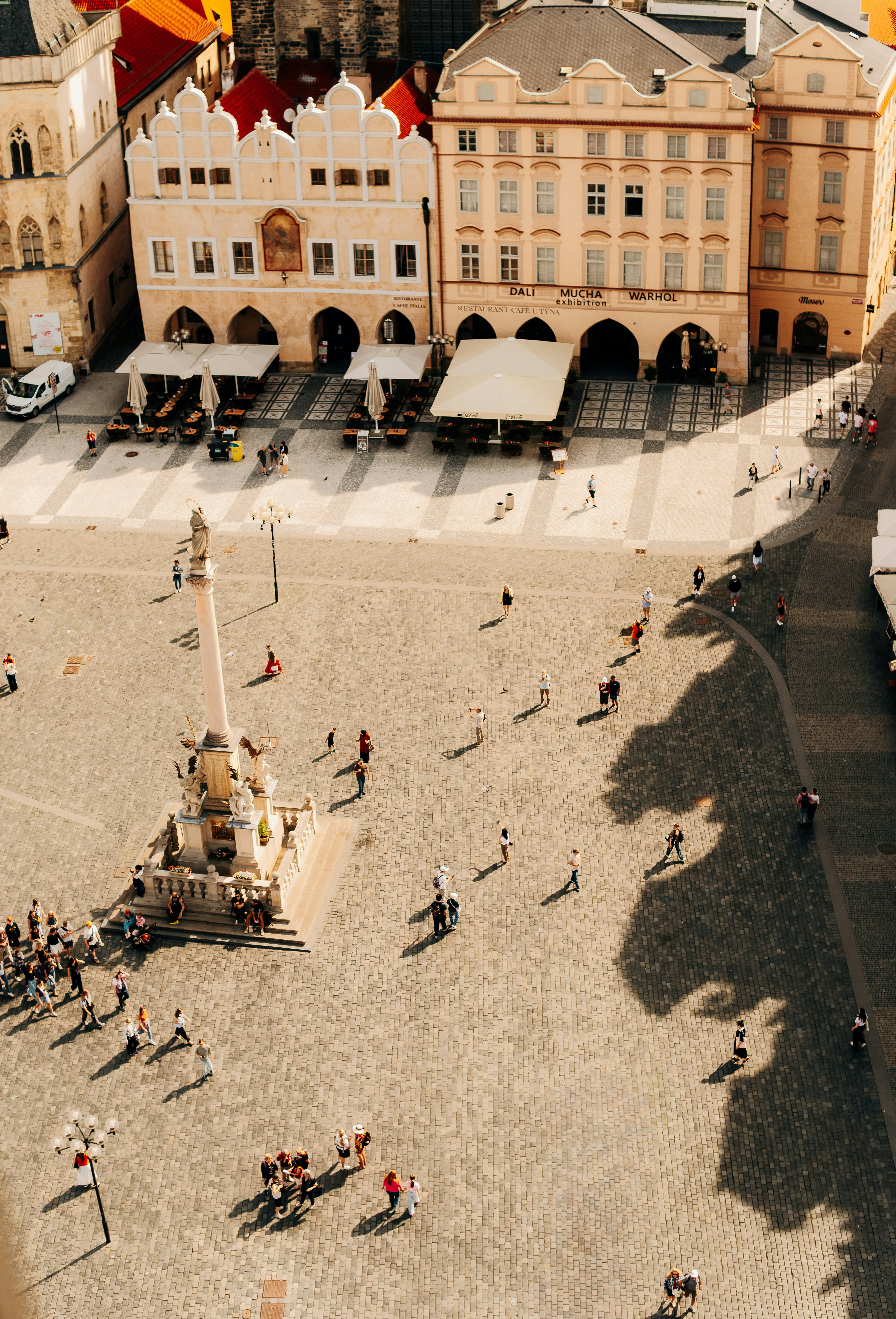 Sunlit historic city square with people and ornate buildings.