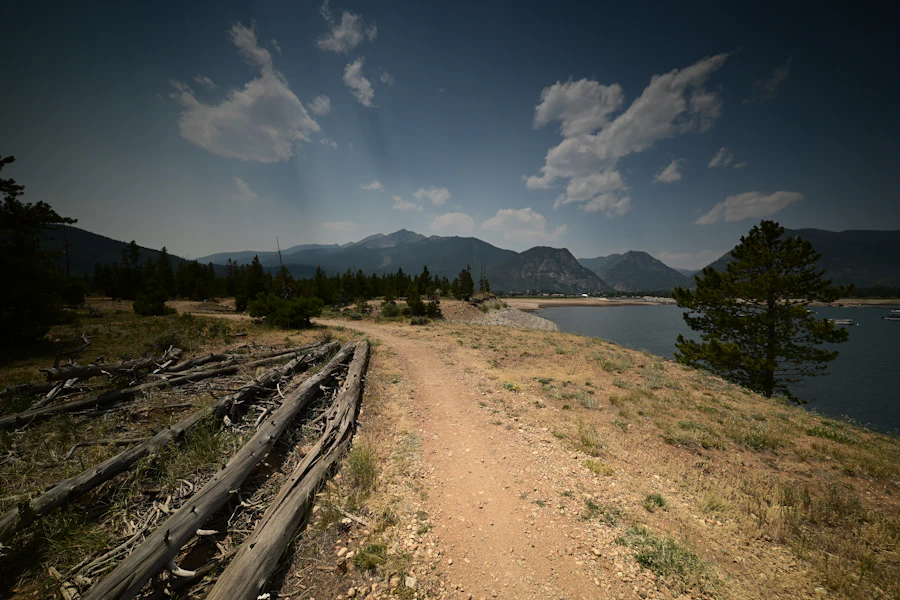 Dirt path beside the water with mountains behind