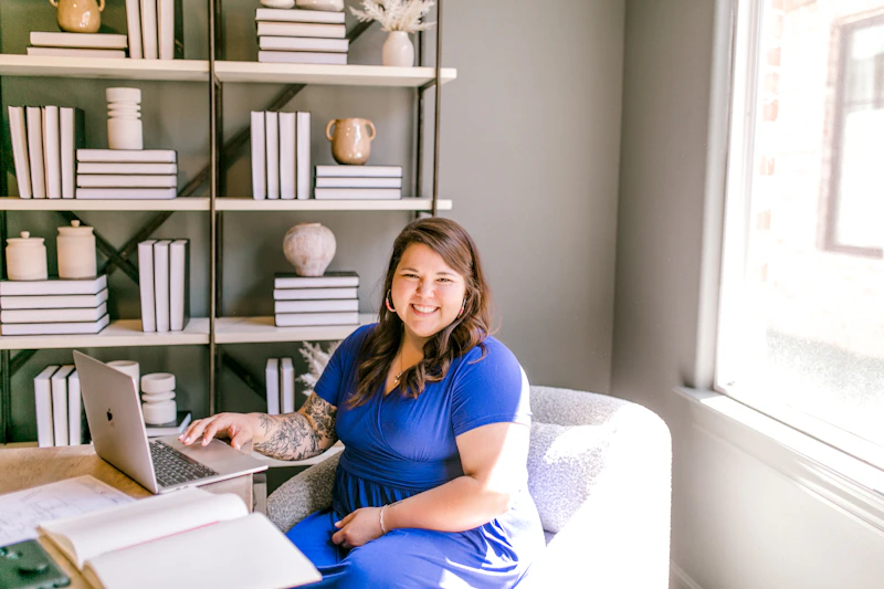 smiling woman working beside books and a laptop
