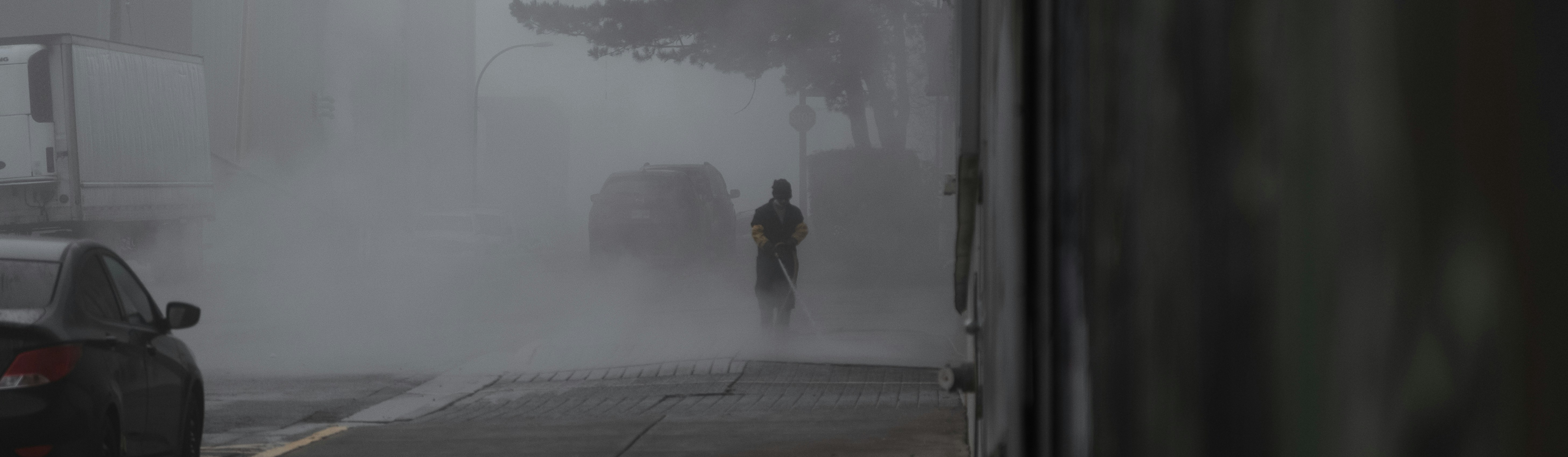 A névoa envolve uma rua com uma pessoa sozinha caminhando.