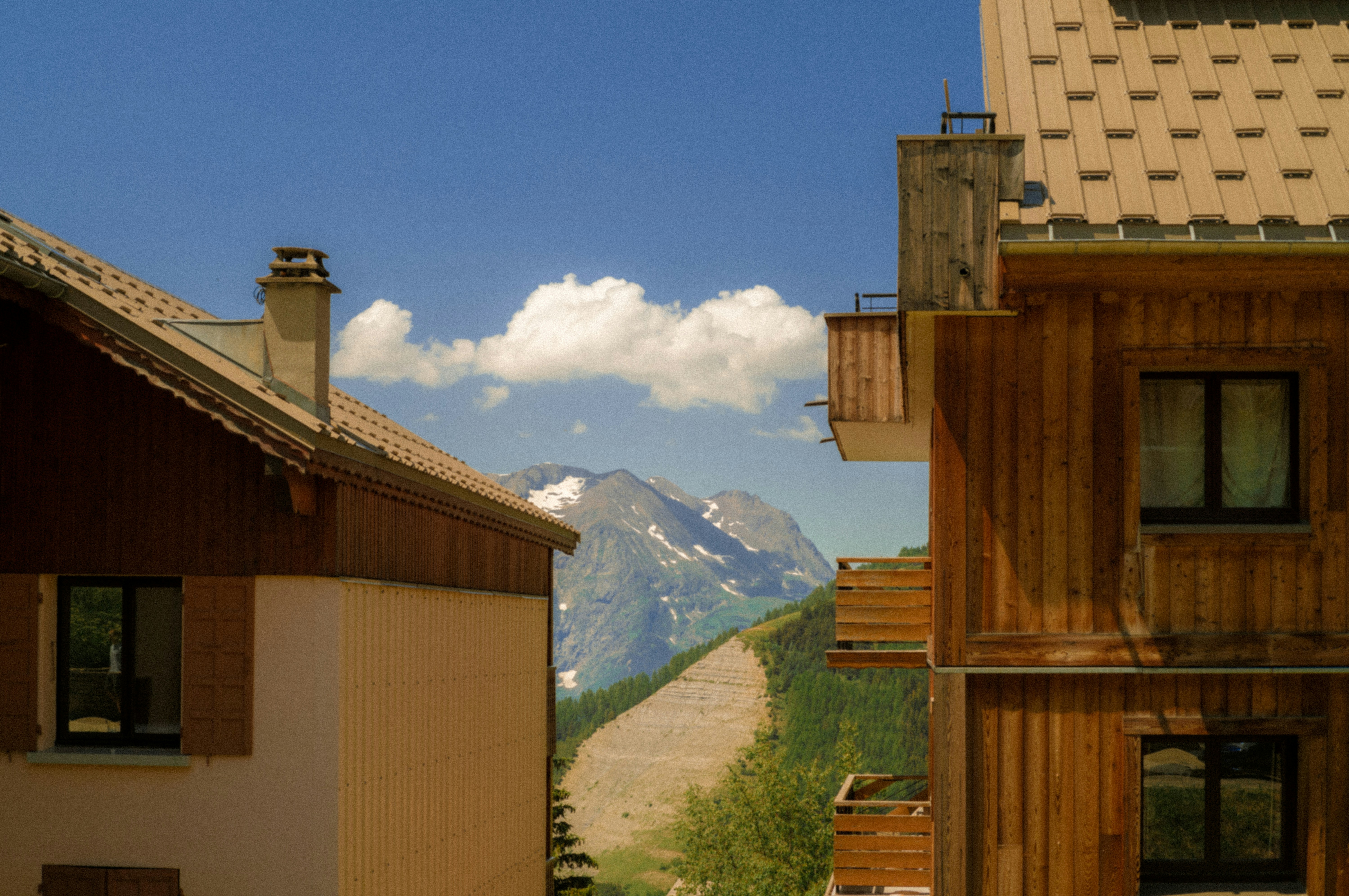 Mountain with ski slope framed by wooden buildings