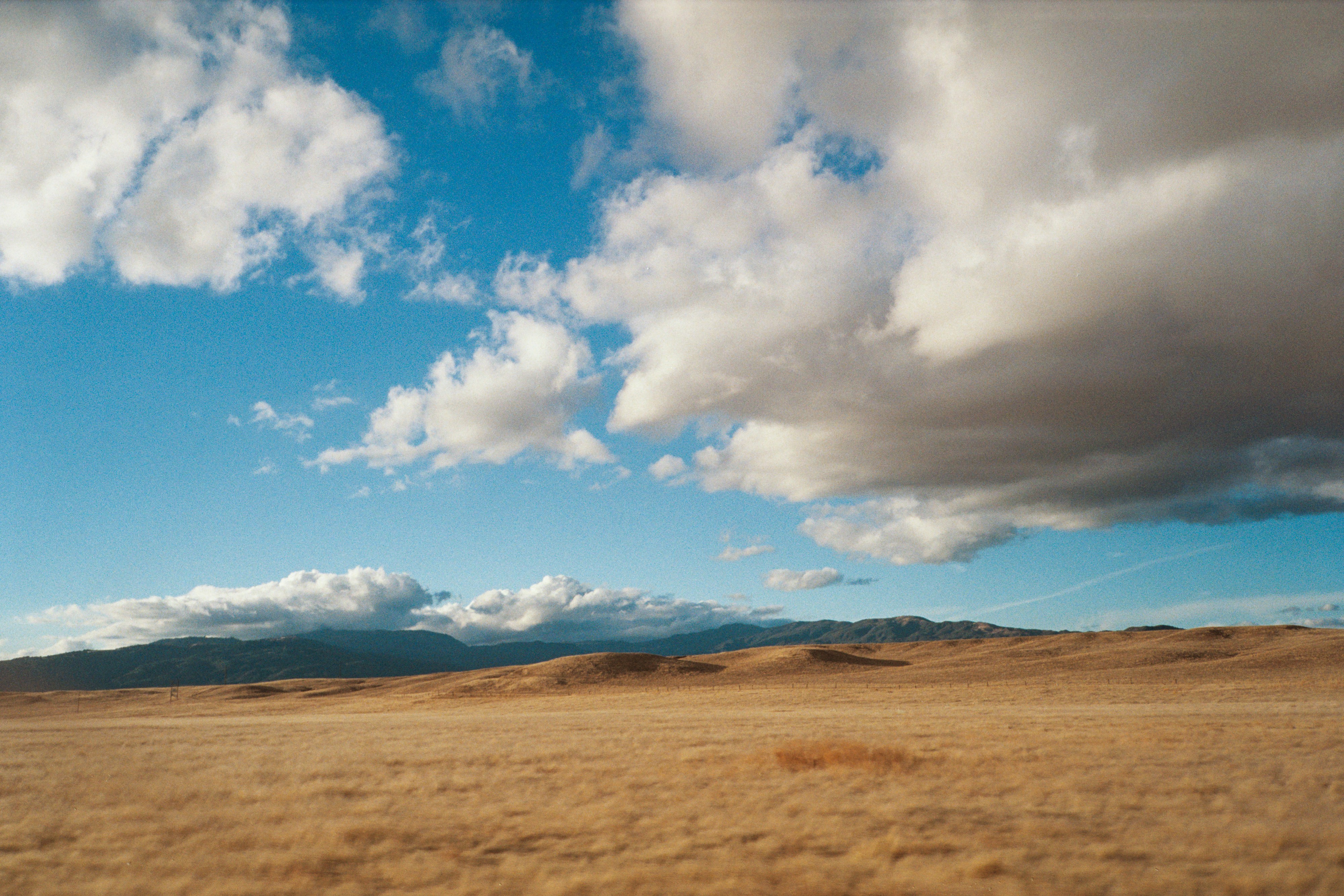 A vast dry plain under a partly cloudy blue sky.