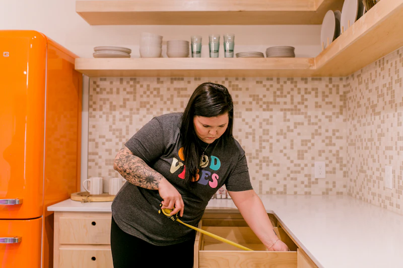 Woman measuring a kitchen drawer while planning home organization