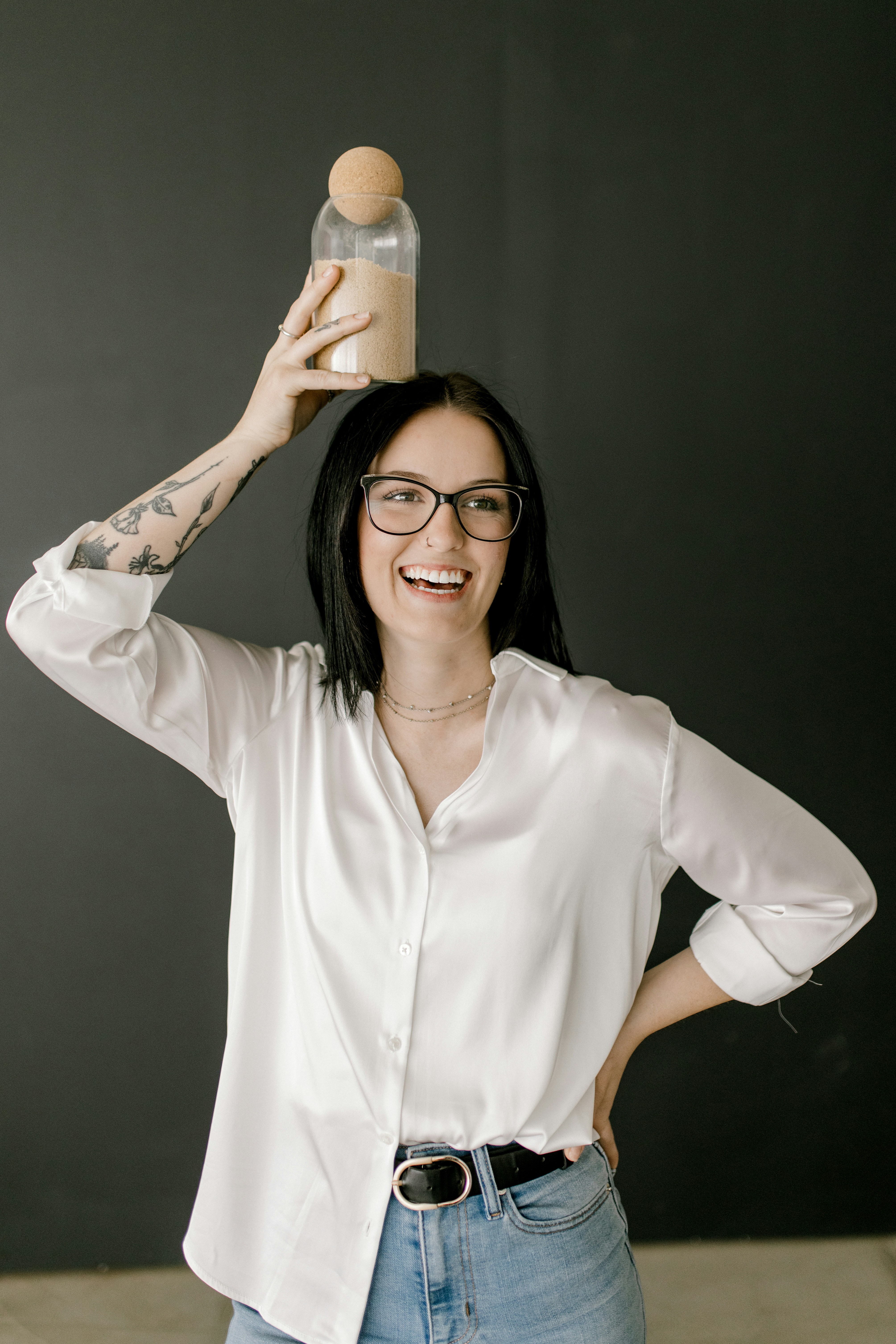 Nadia, laughing in a white shirt, balances a storage jar on her head