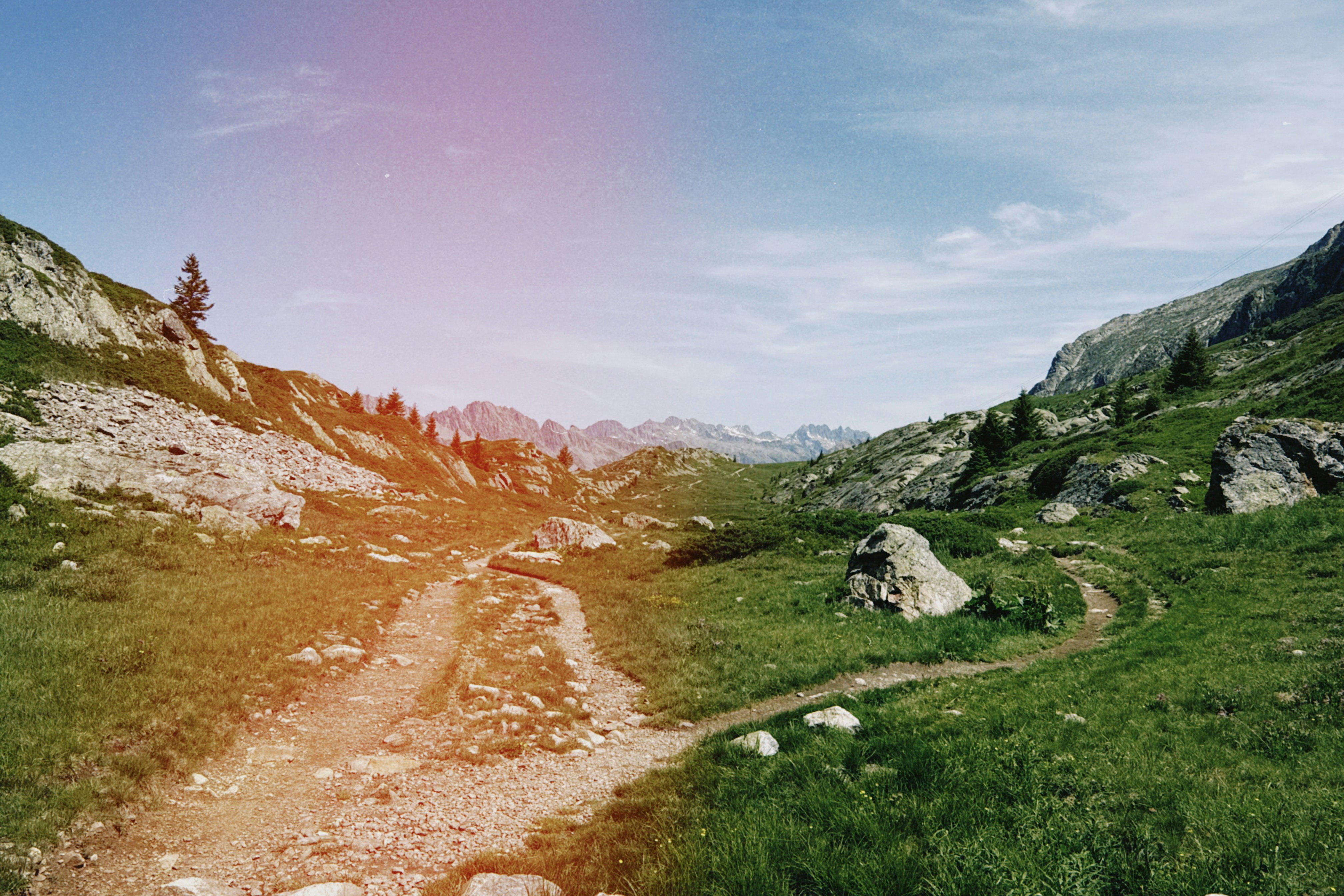 Winding dirt path through green mountain valley