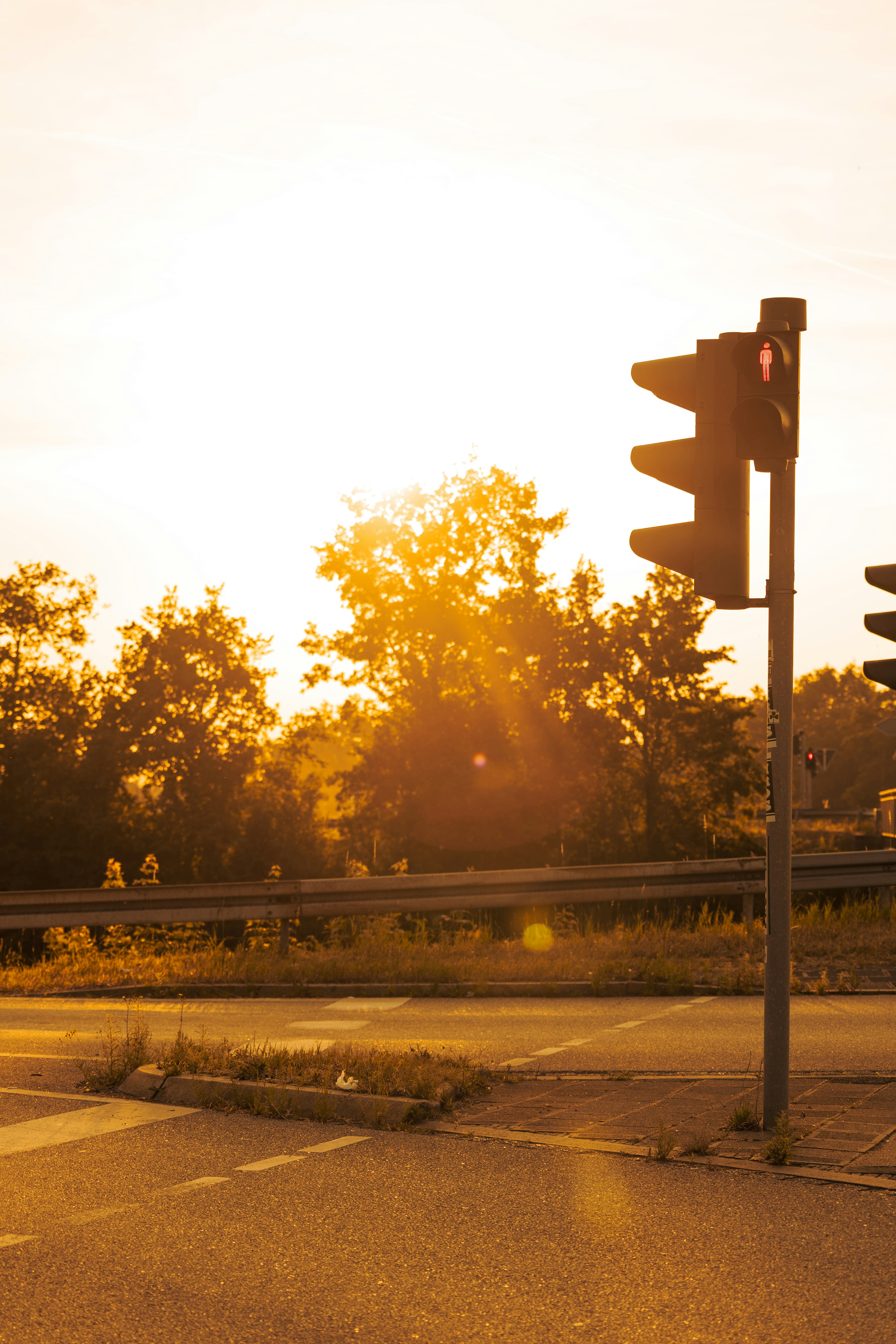 Pedestrian traffic light glowing red against a golden sunset