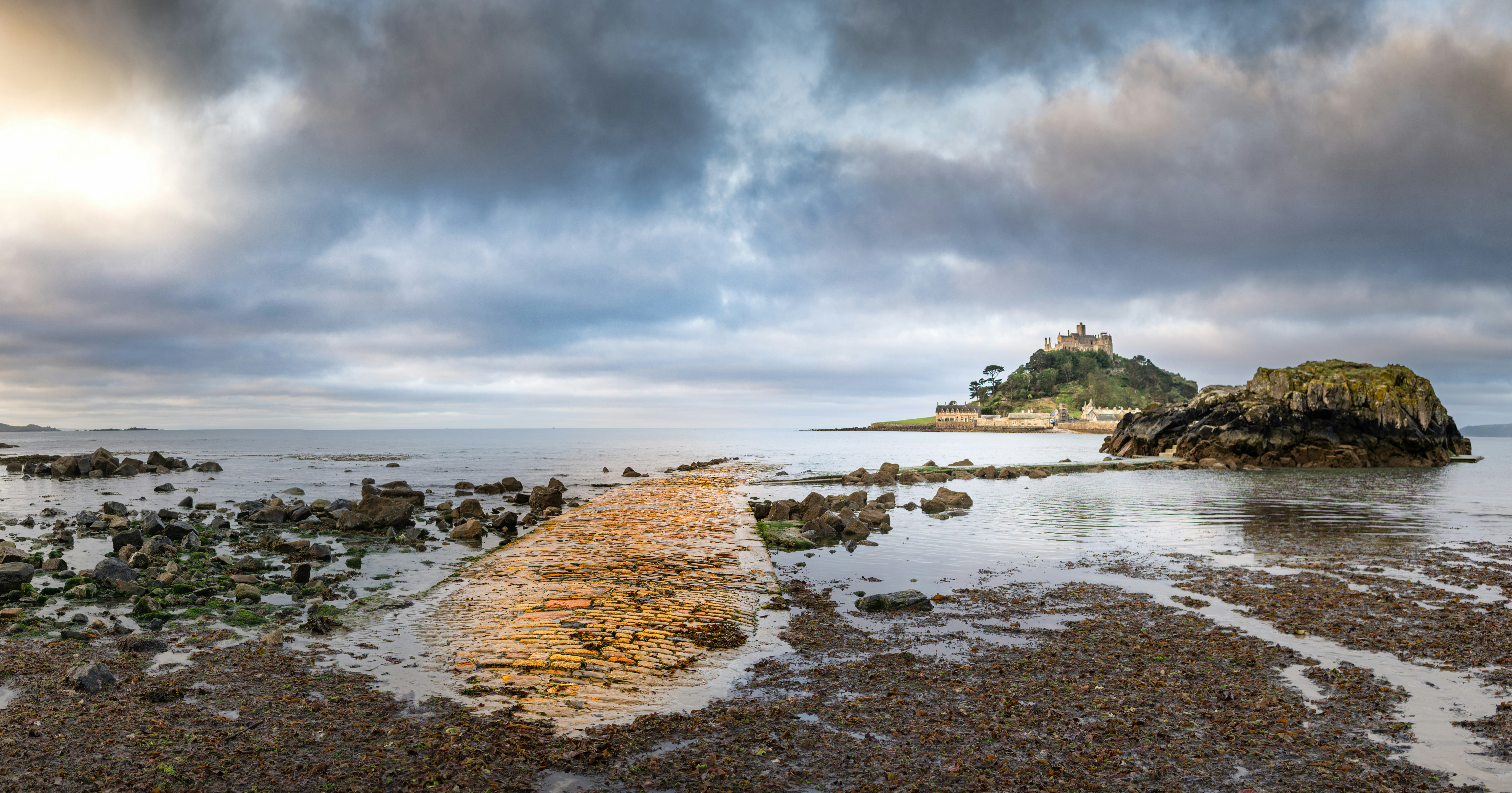 Rocky causeway stretches towards a distant island castle.