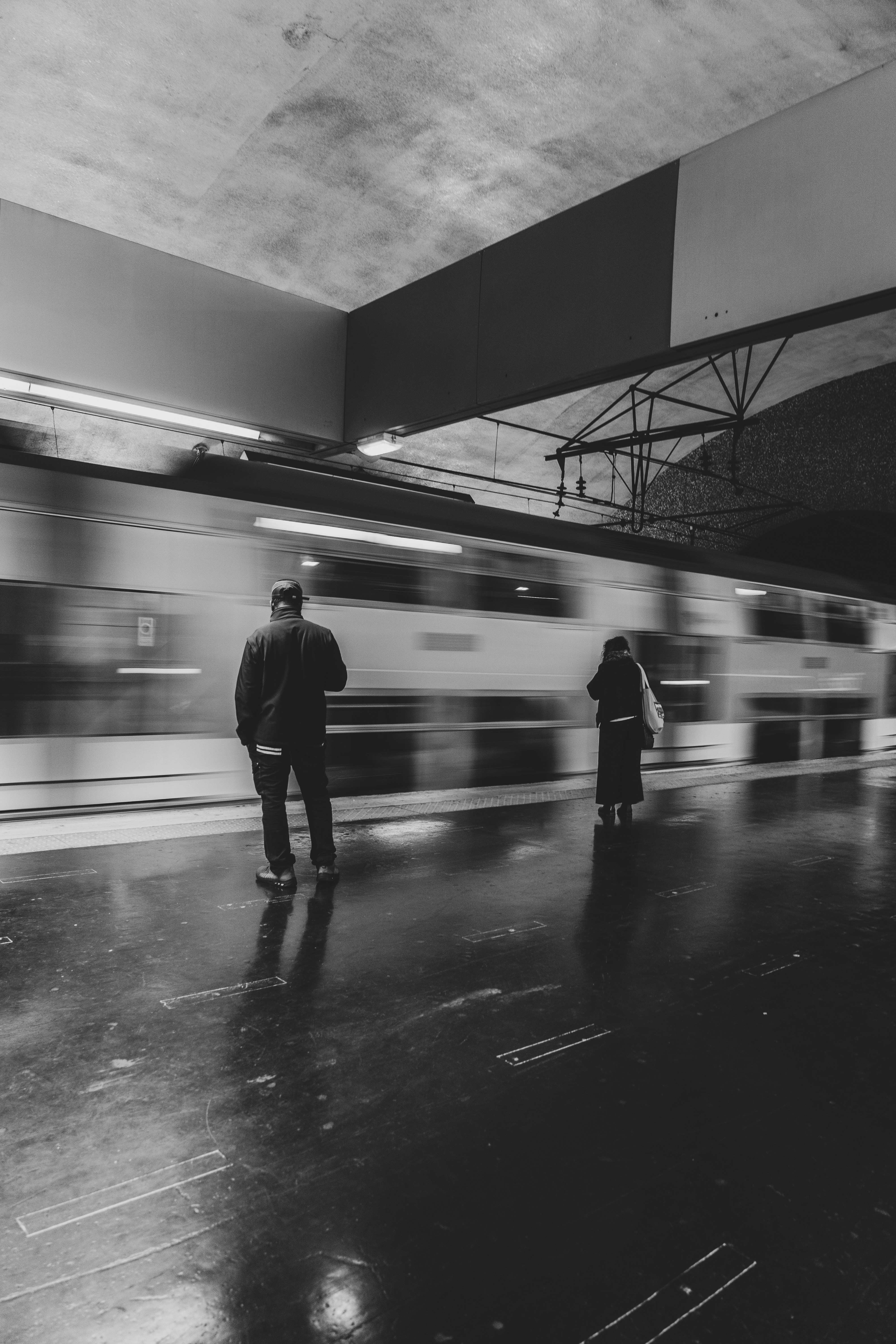 El tren del metro pasa borroso junto a dos figuras en un andén de la estación