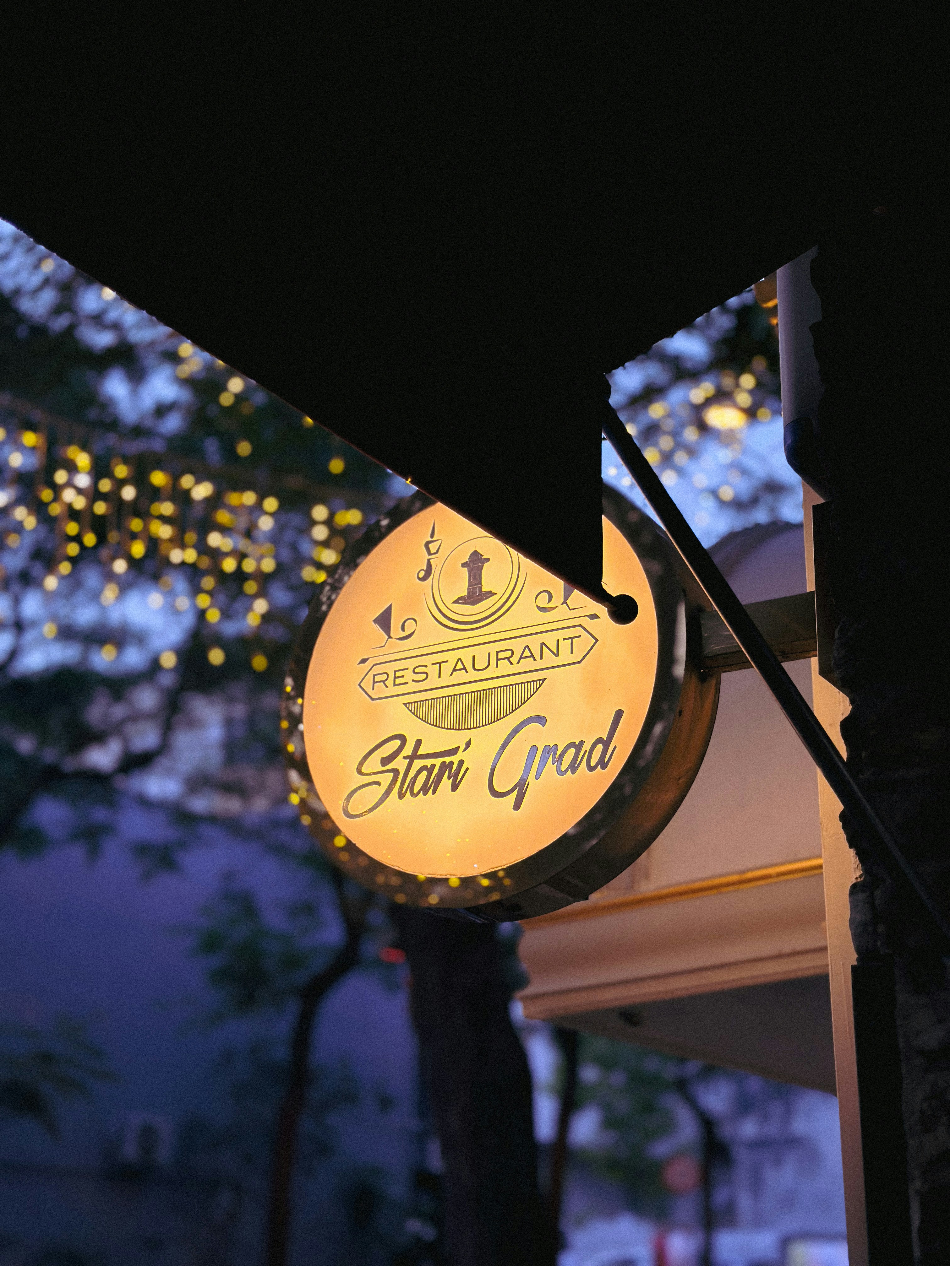 Un cartel iluminado de restaurante "stari grad" por la noche.