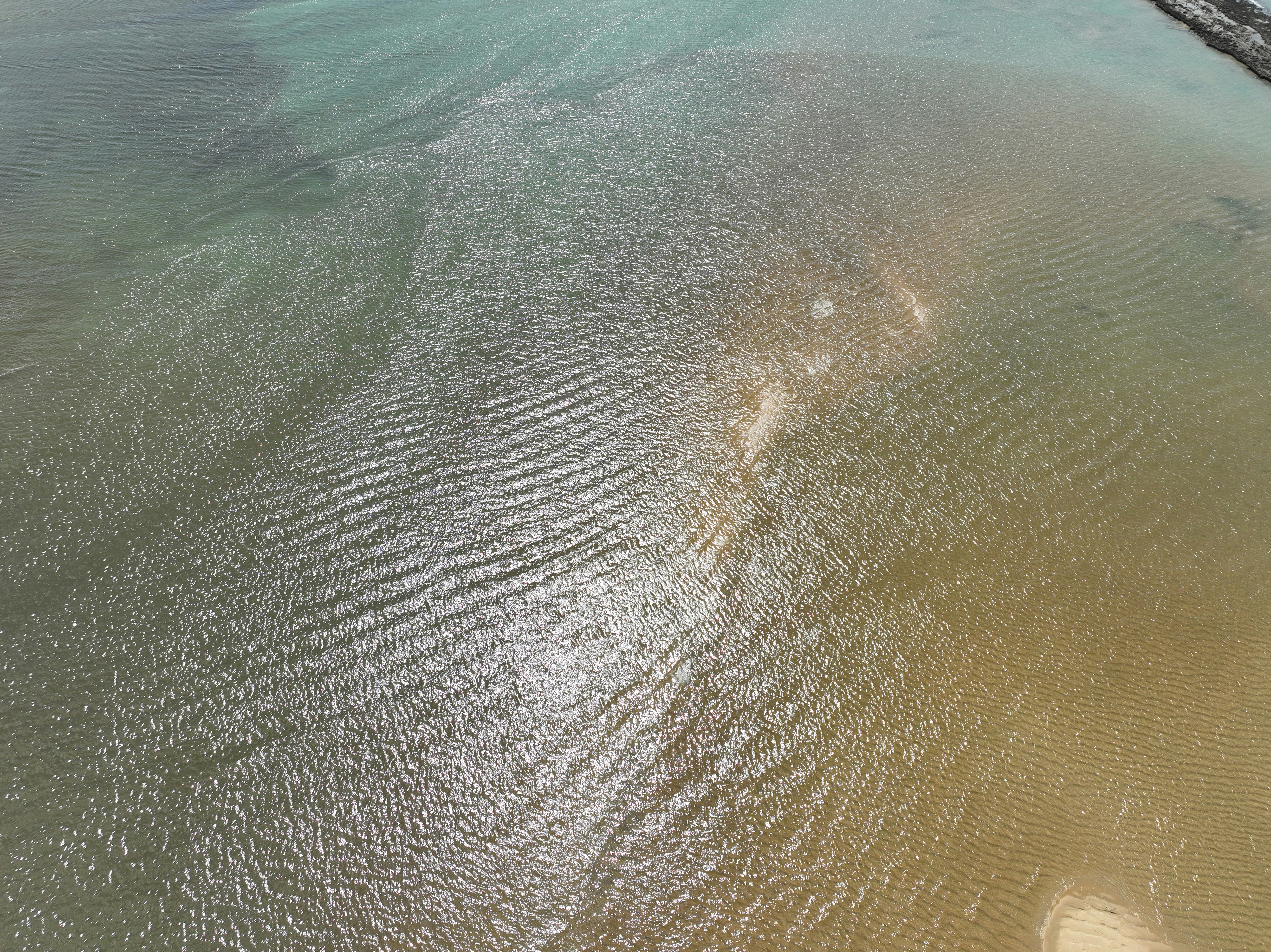 Aerial view of clear shallow water with ripples and sand