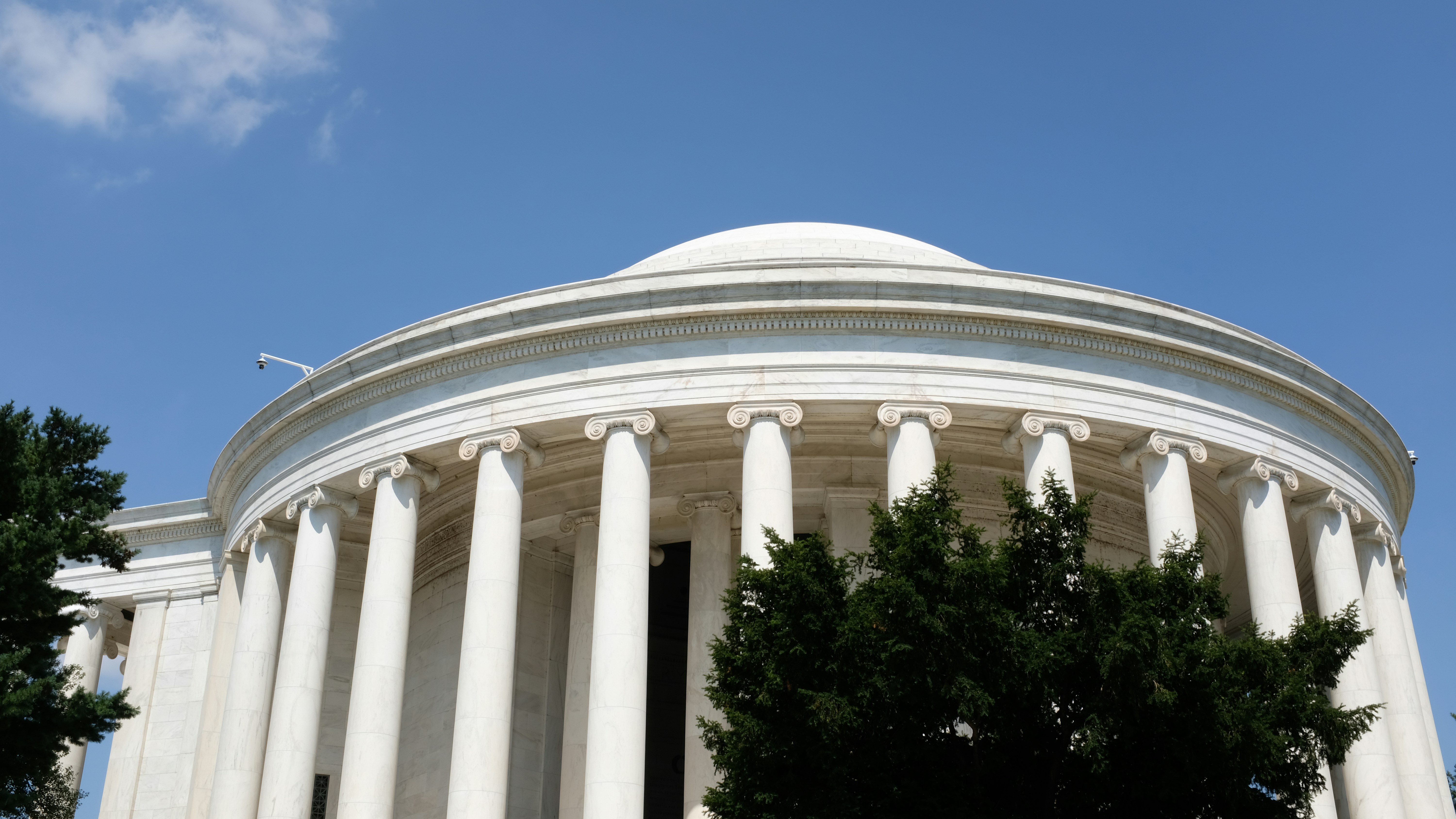 Jefferson memorial with columns and dome against a blue sky.