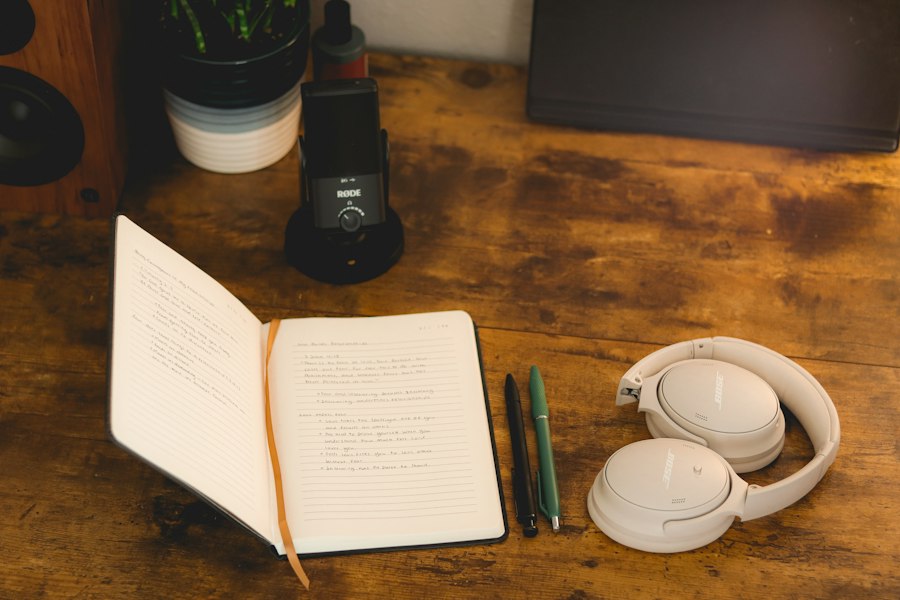 Open notebook, pens and headphones on a rustic wooden desk