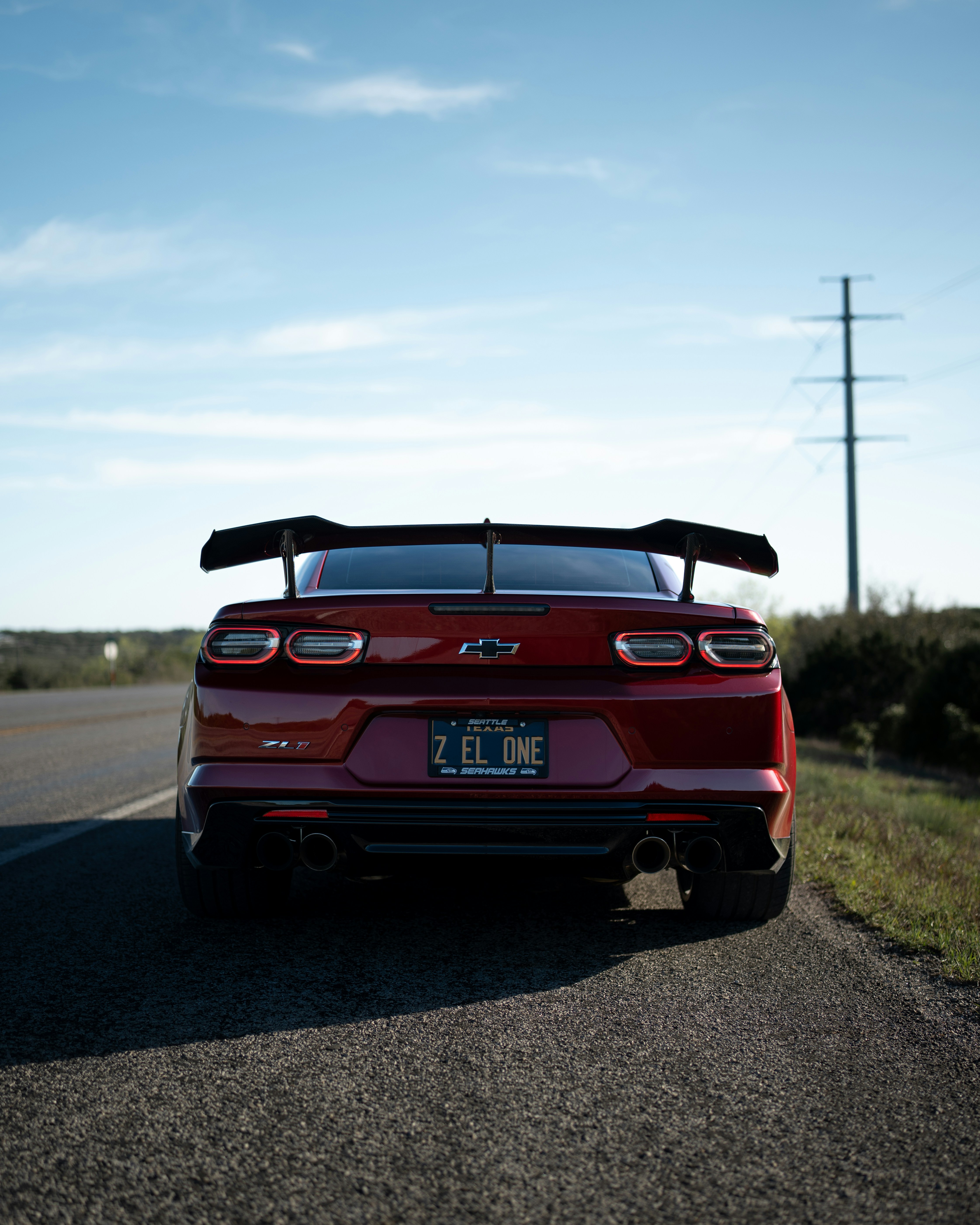 Red chevrolet camaro zl1 with spoiler on a rural road