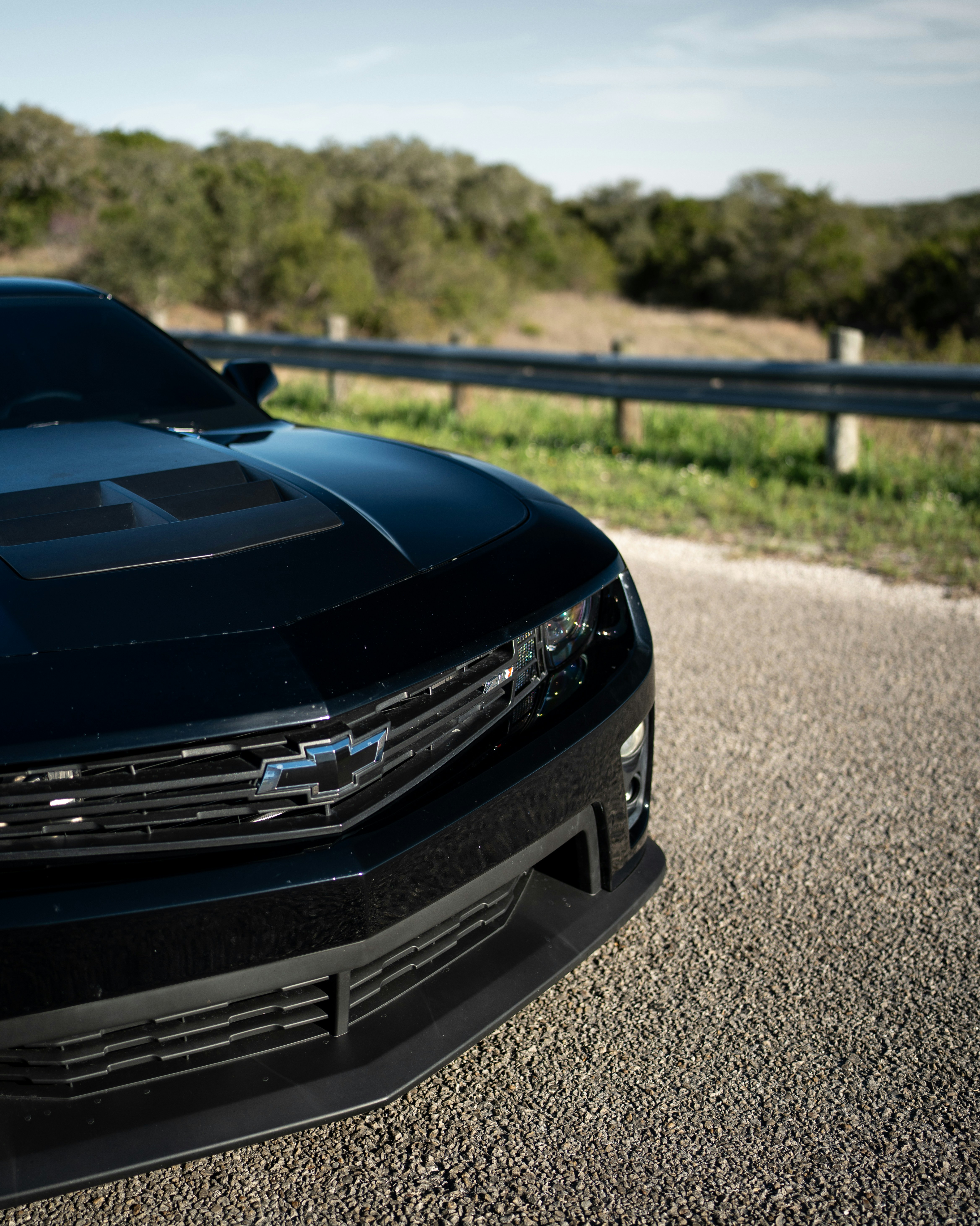 A sleek black chevrolet camaro parked on a sunny road