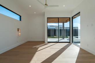 Modern empty room with sliding glass doors and sunlit floor