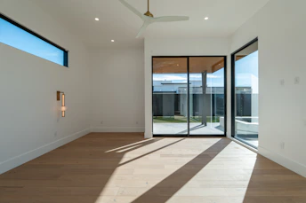 Modern empty room with sliding glass doors and sunlit floor